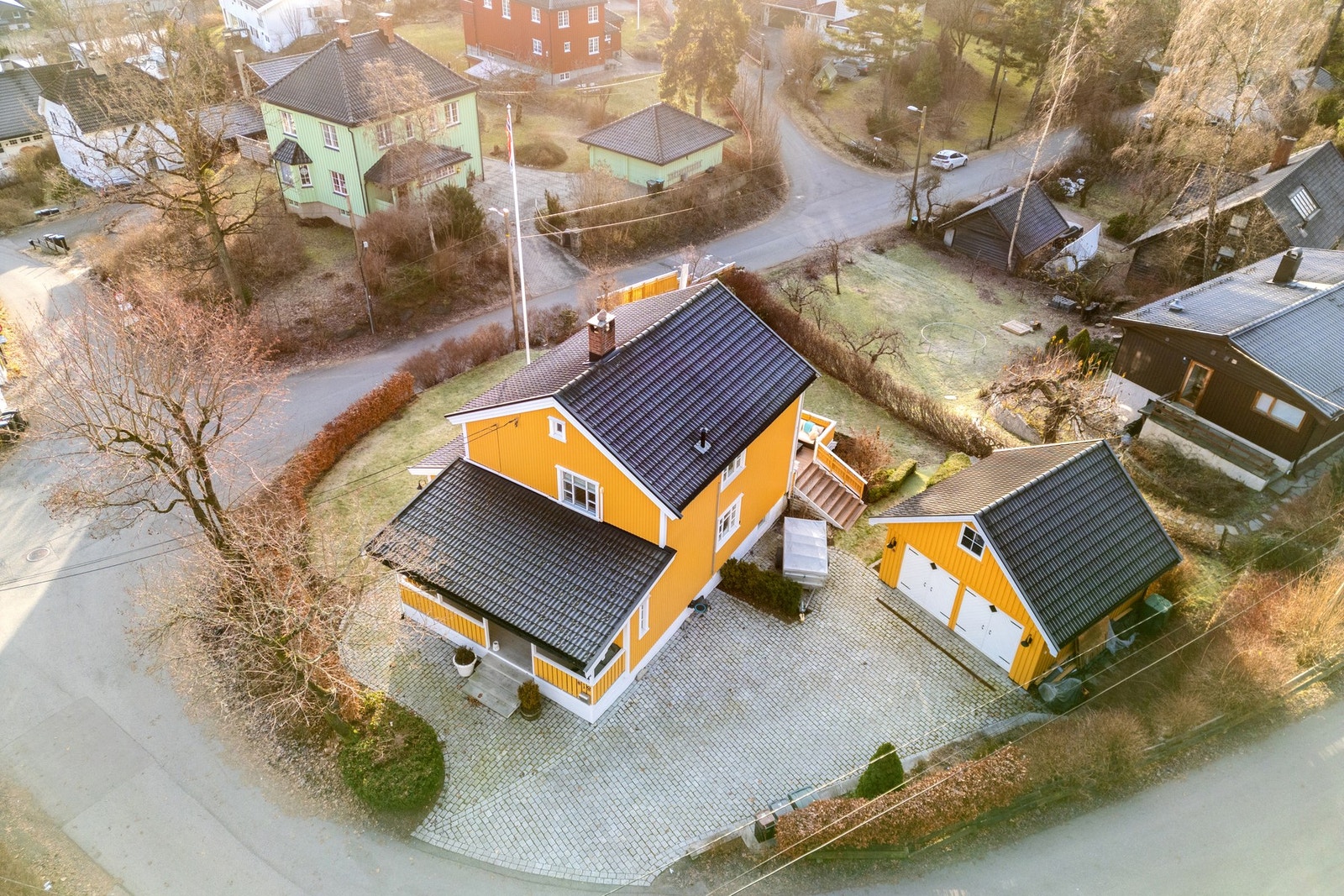 Tomten er pent opparbeidet med steinsatt gårdsplass, gressplen, beplantning og plattinger. Galleribilde