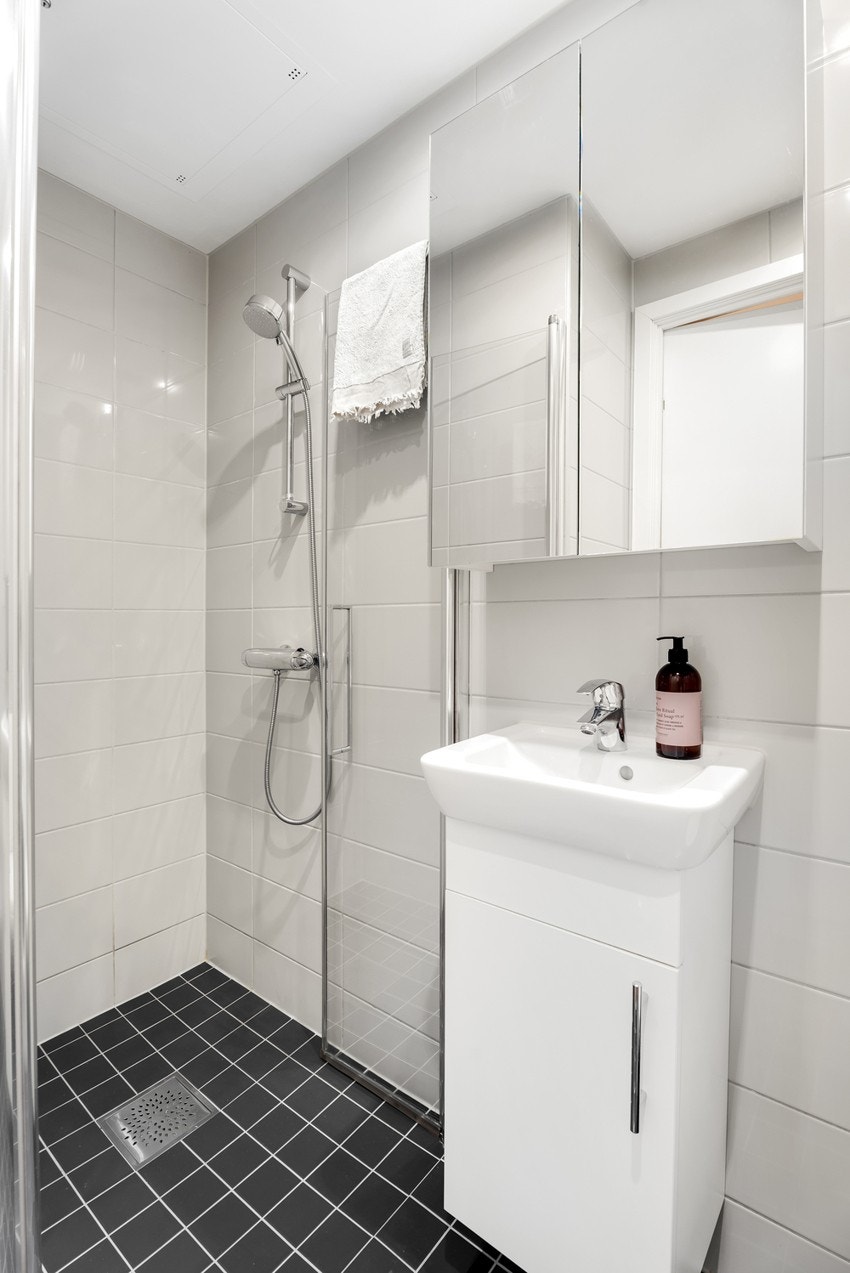 Baderommet har innfellbare glassdører i dusjhjørnet, vegghengt toalett og opplegg for vaskemaskin og tørketrommel Galleribilde