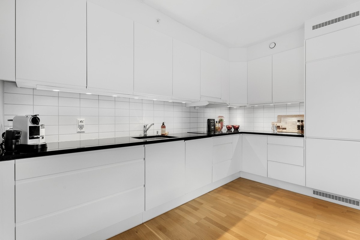 Kjøkkeninnredningen er fra 2015 og kombinerer klassiske, glatte fronter med moderne steinbenkeplater Galleribilde