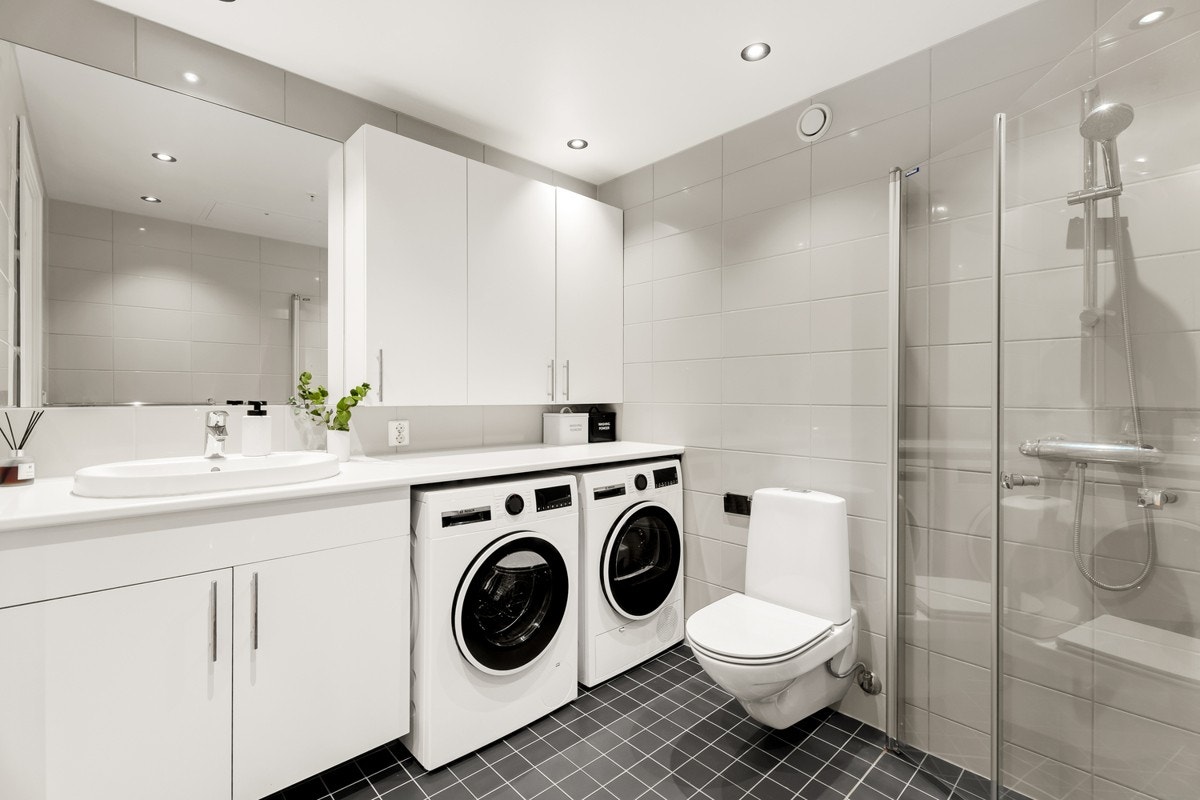Badet har vegghengt toalett, opplegg til vaskemaskin og tørketrommel, og dusjhjørne med praktiske innfellbare glassdører Galleribilde
