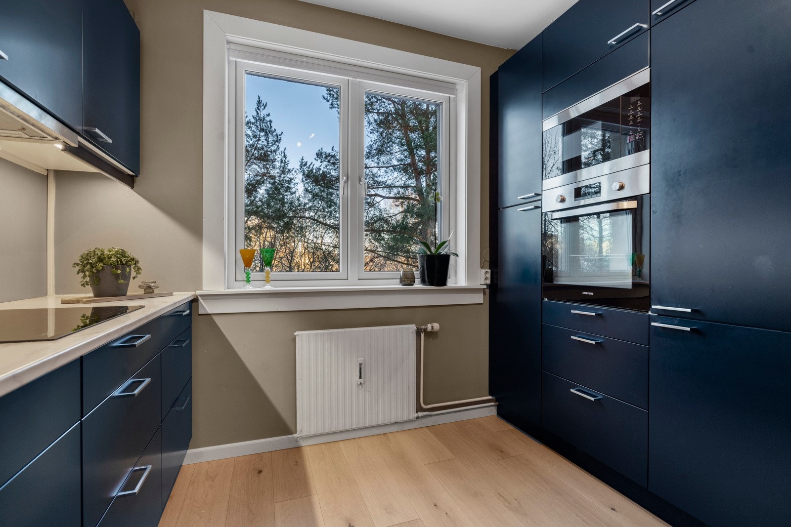 Laminat benkeplate med nedfelt kum i rustfritt stål samt integrert platetopp med induksjon, stekeovn, mikrobølgeovn, oppvaskmaskin og kjøle-/fryseskap. Galleribilde