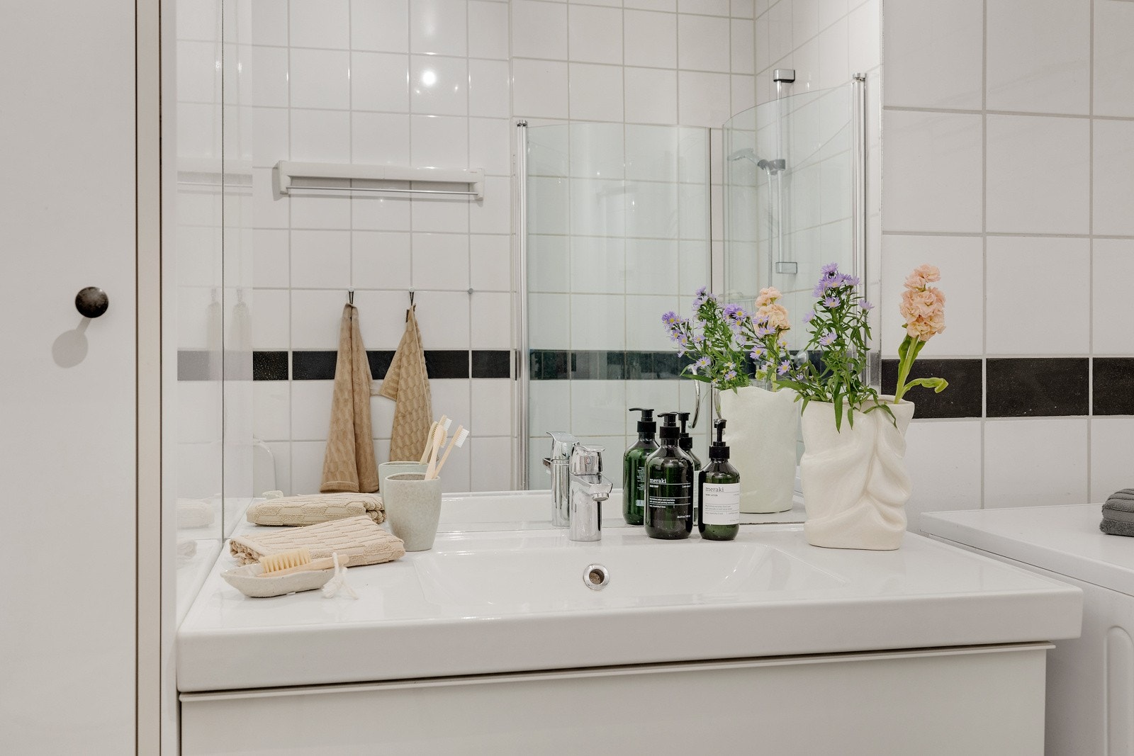 Badet inneholder baderomsinnredning med skuffer og heldekkende servant, speil med overbelysning, toalett og dusjhjørne med innfellbare dører i glass. Galleribilde