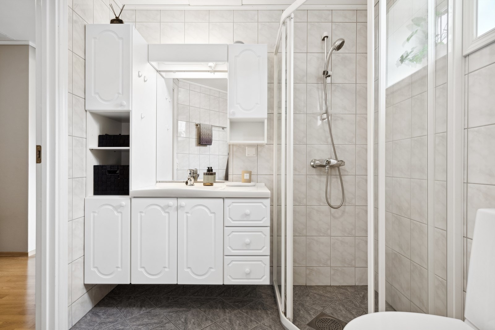 Badet er helfliset med grå gulvfliser og hvite veggfliser Galleribilde