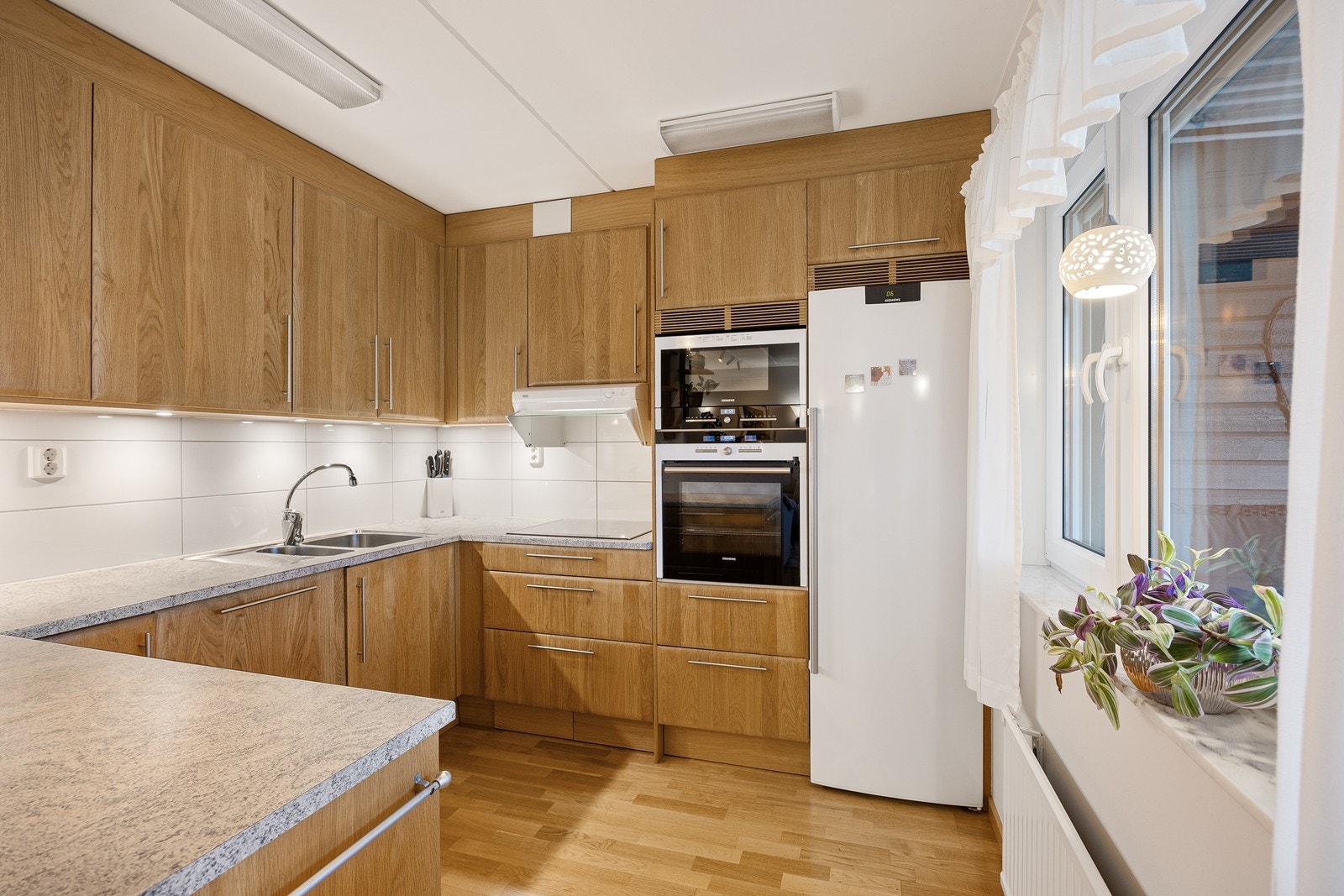 Innredningen har glatte eikefronter og grå laminatbenkeplate med dobbel oppvaskkum. Galleribilde