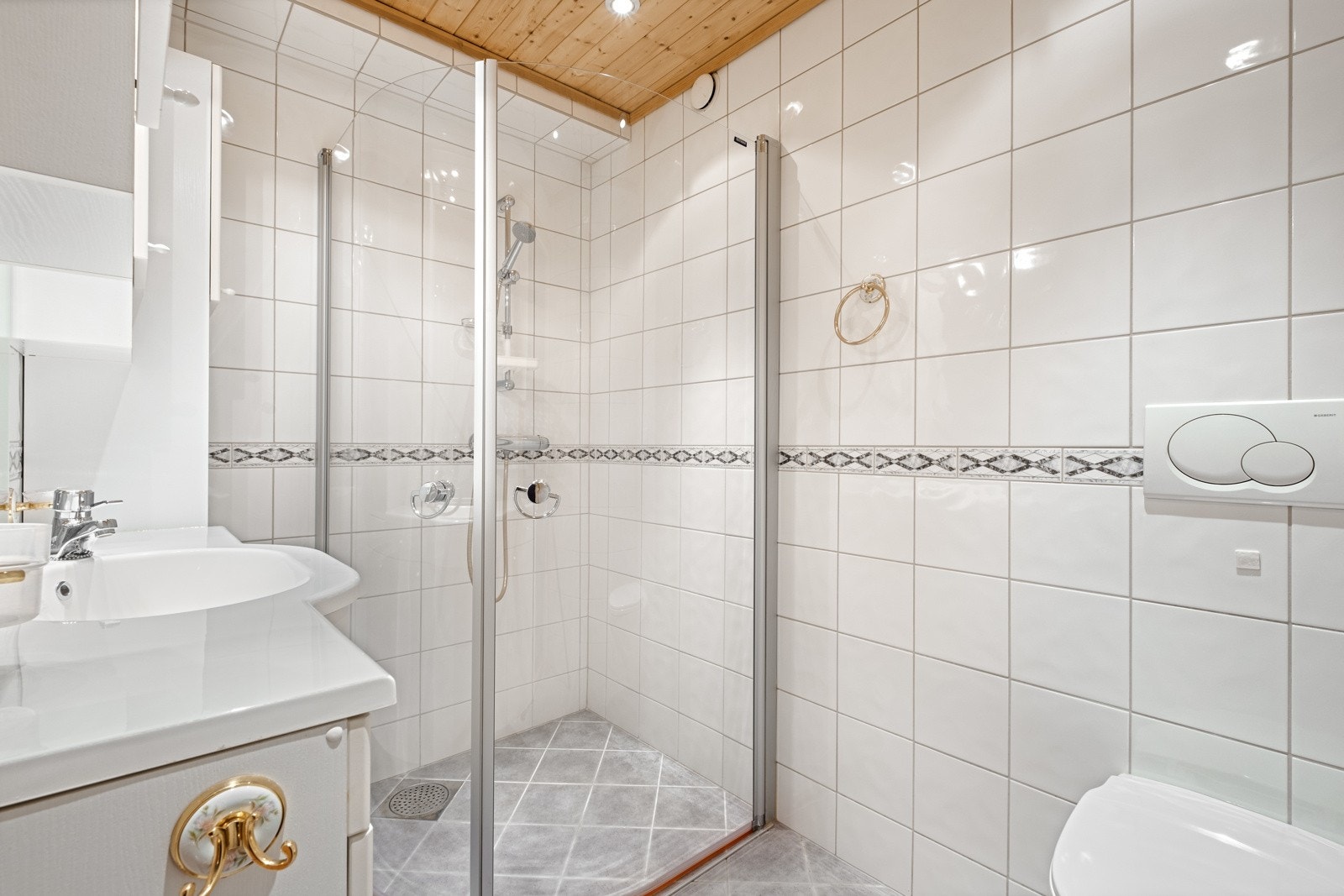 Flislagt bad utstyrt med dusj med innfellbare glassdører, servantskap, speil og toalett. Gulvvarme. Galleribilde