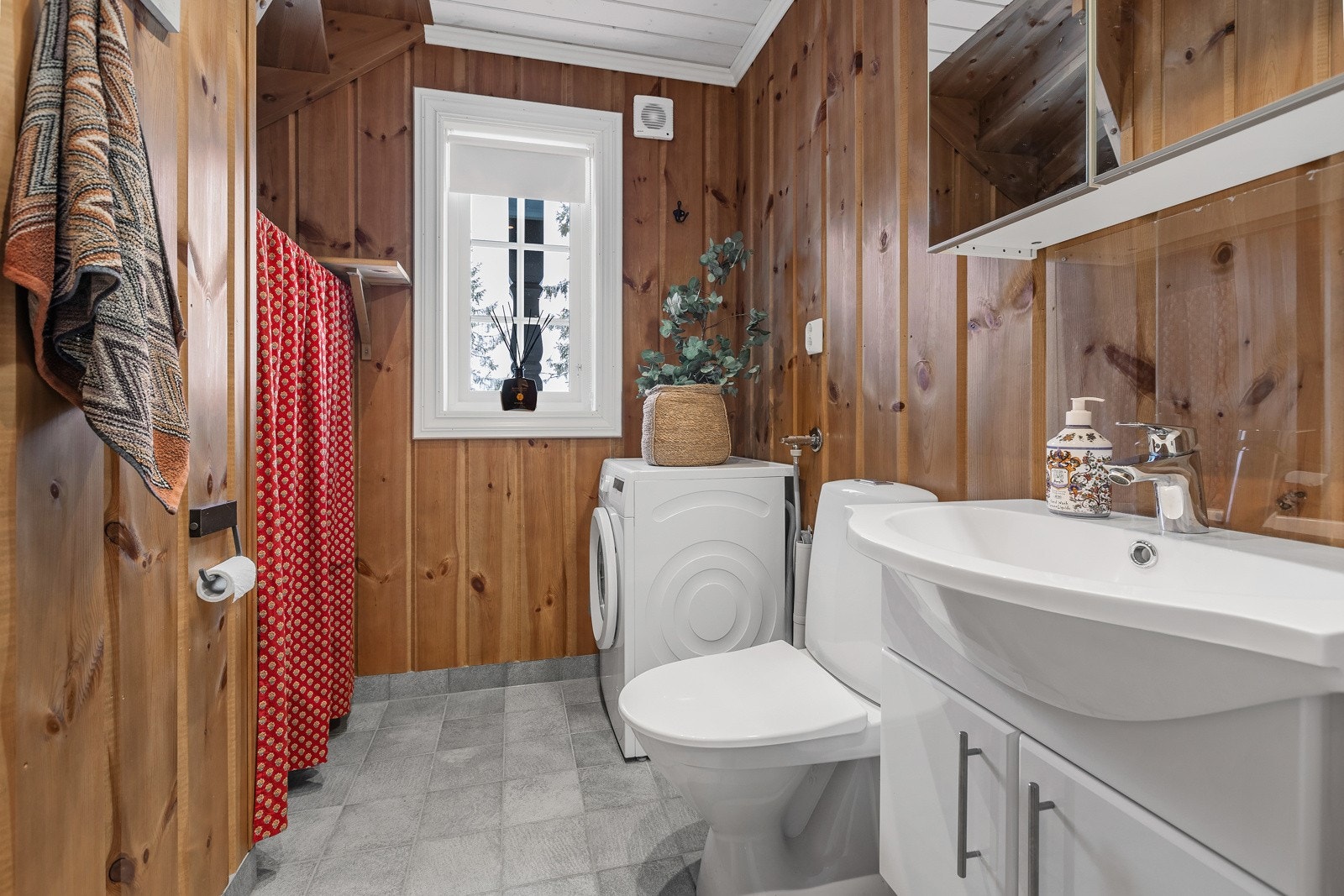 Vaskerommet/toalettrom med flislagt gulv og panel på veggene. Galleribilde