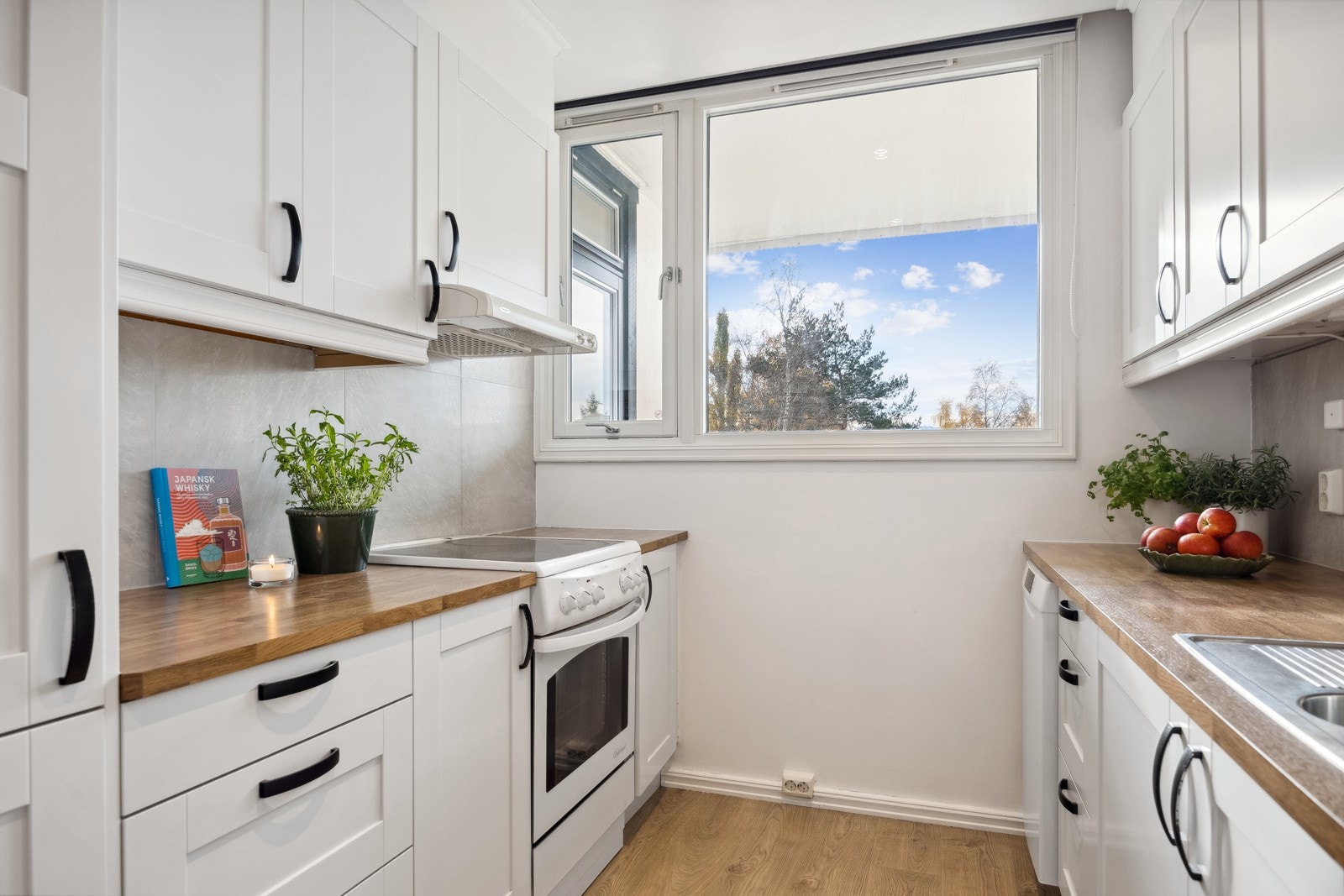 Glatte innredningfronter med sorte håndtak, og benkteplate som matcher gulvet som skinner fint med gjennomstrømningen av naturlig lys. Galleribilde