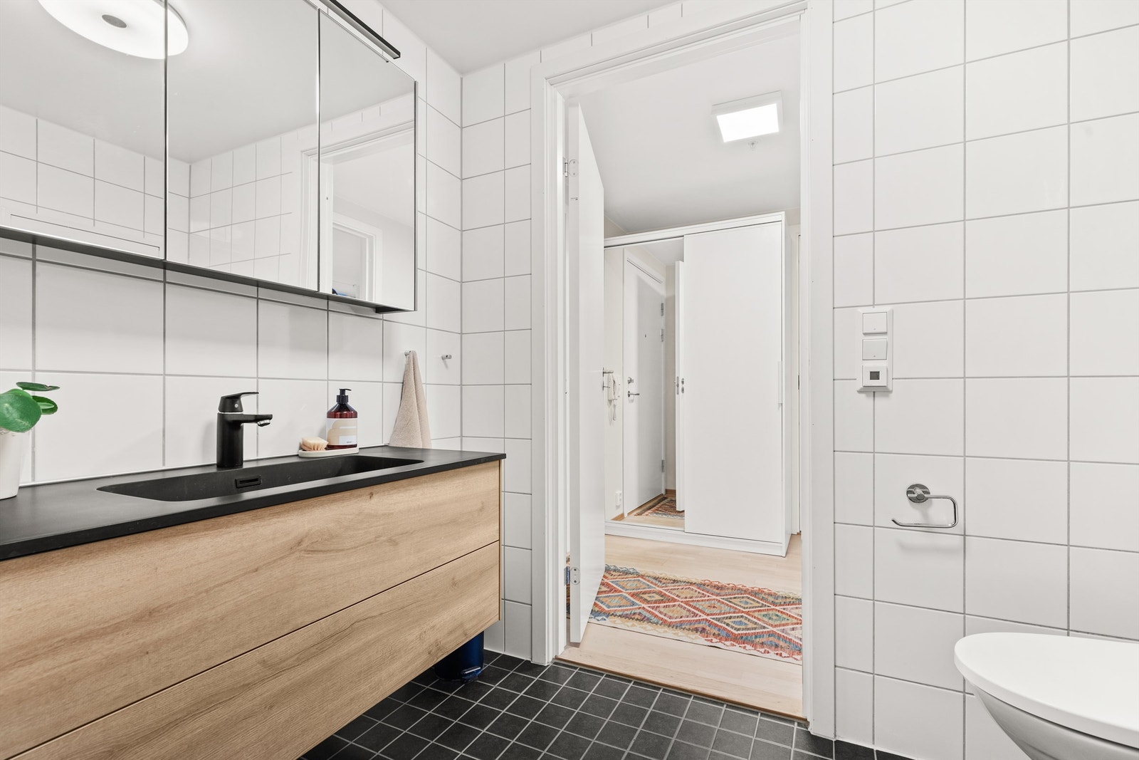 Badet er pent flislagt på gulv og vegger med varme i gulvet. Innredningen består av vegghengt servantskuffer med nedfelt servant Galleribilde