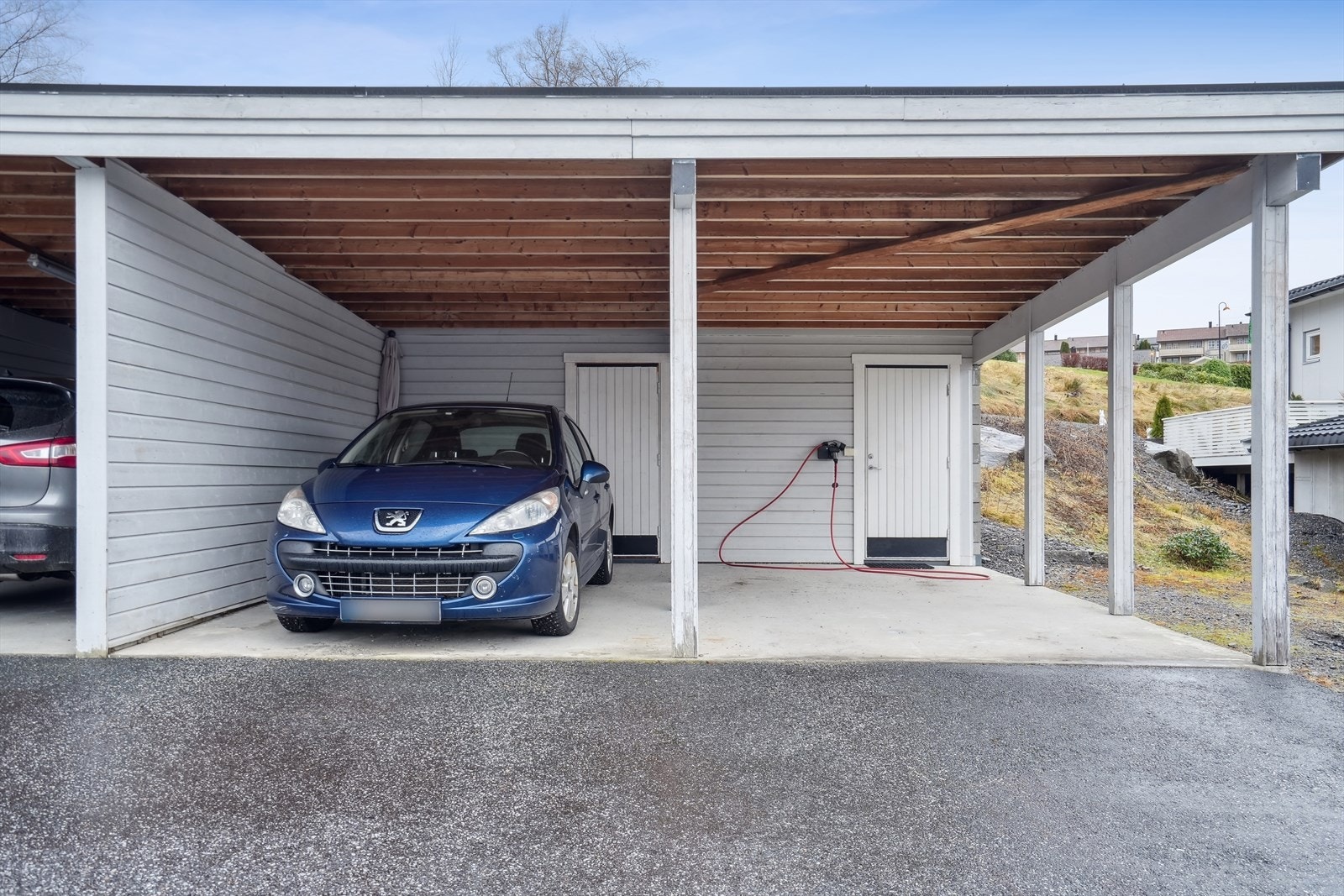 Leilighetens carport er der bilen er parkert - og med praktisk sportsbod i bakkant Galleribilde