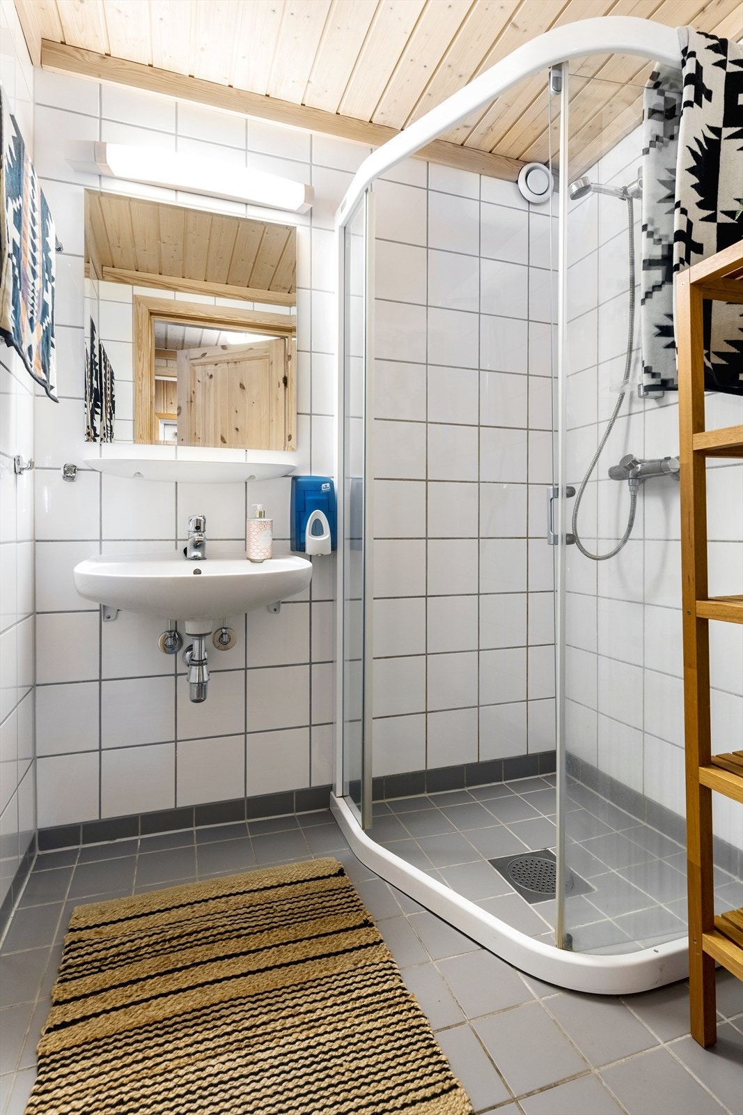 Flislagt bad med dusjhjørne og servant med speil og overlys. Galleribilde