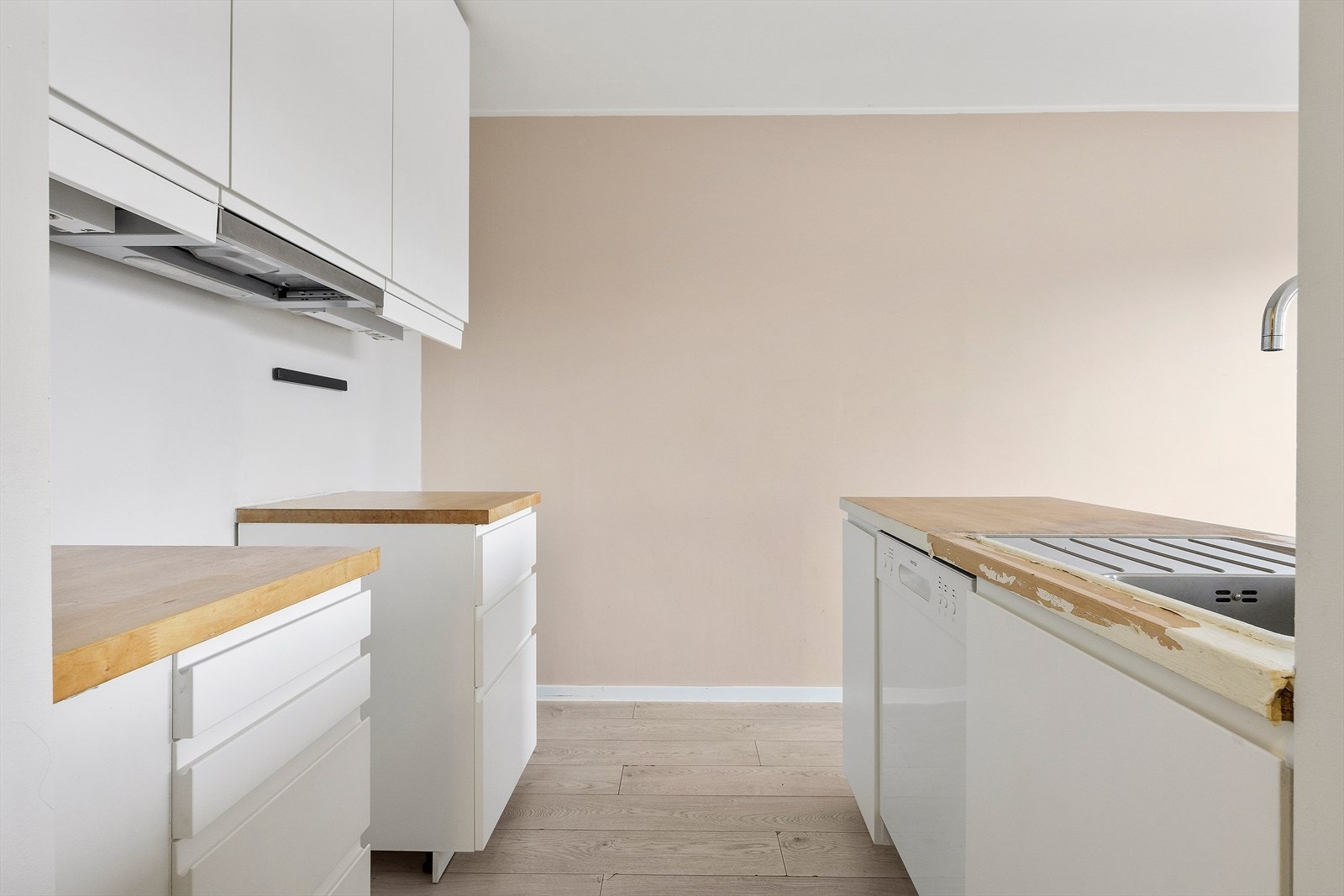 Hvit, stilren kjøkkeninnredning med rikelig skap- og benkeplass Galleribilde