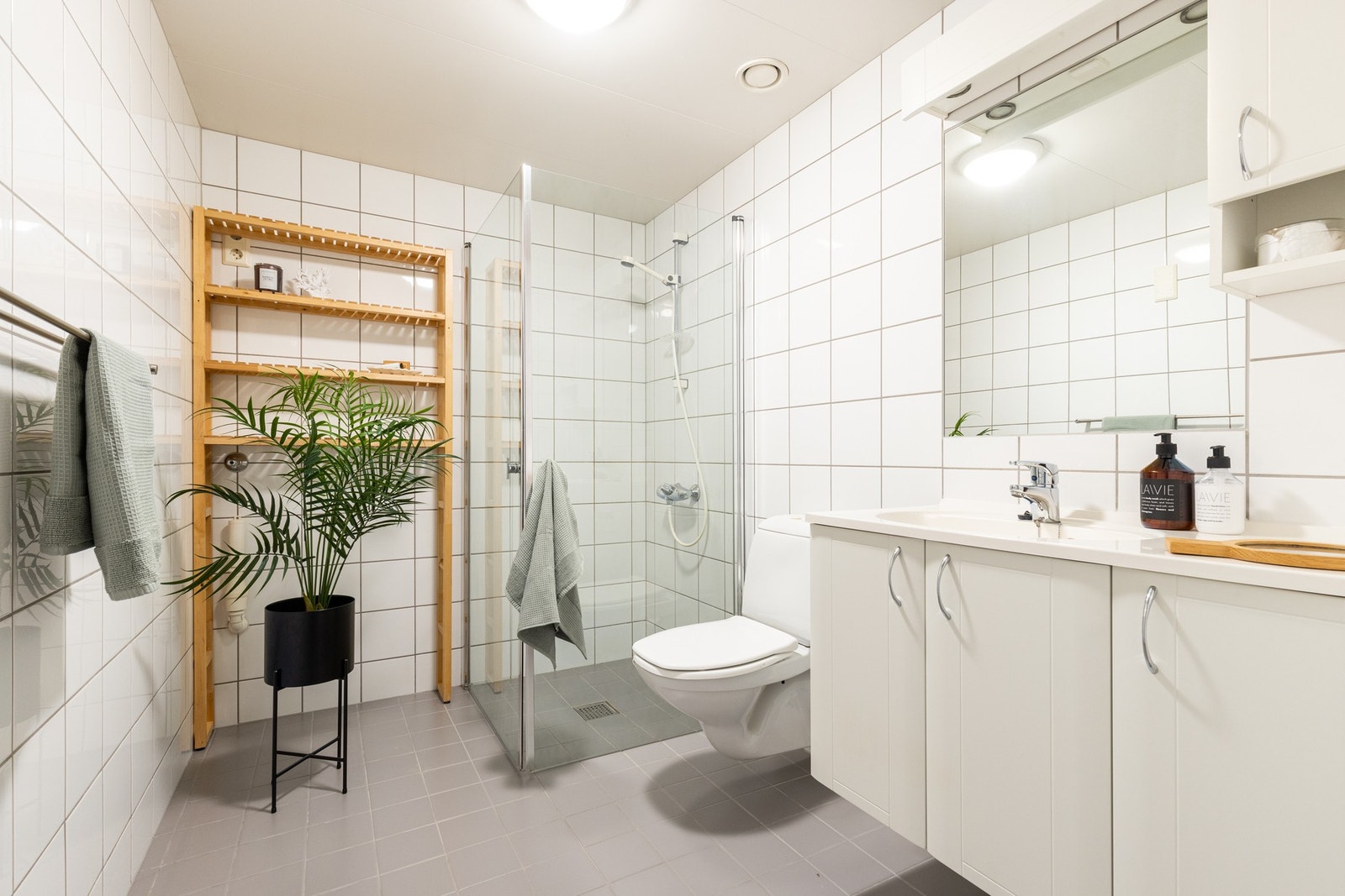 Boligen har et lyst bad med inngang fra entréen. Badet er bygget opp med hvite fliser på vegg og grå fliser på gulv med gulvvarme. Innredningen består av servant med underskap og speil med belysning. Galleribilde