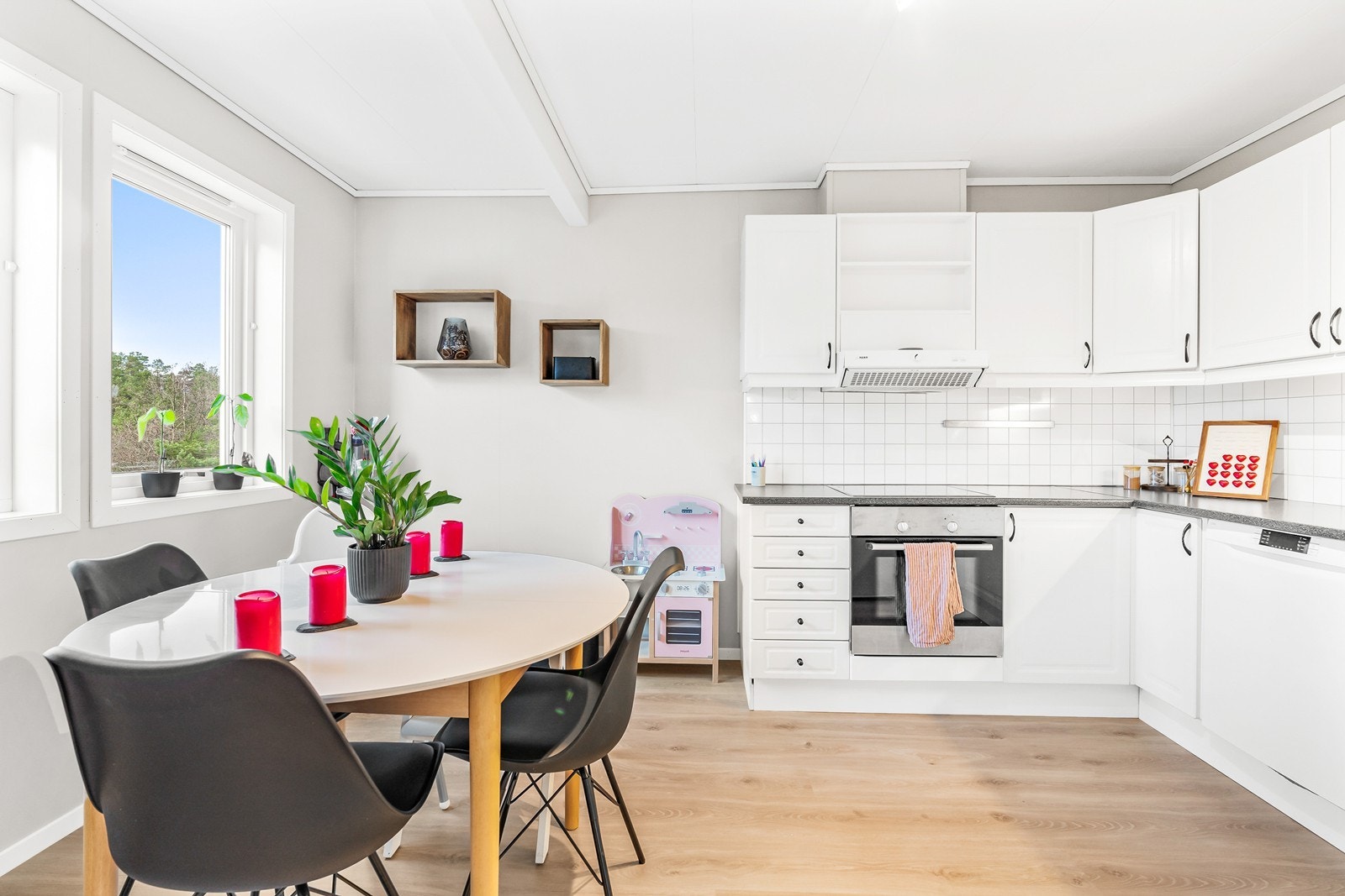 Kjøkkenet har lyse, profilerte fronter og laminert benkeplate med kjøkkenplater på vegg over benkeplate. Galleribilde