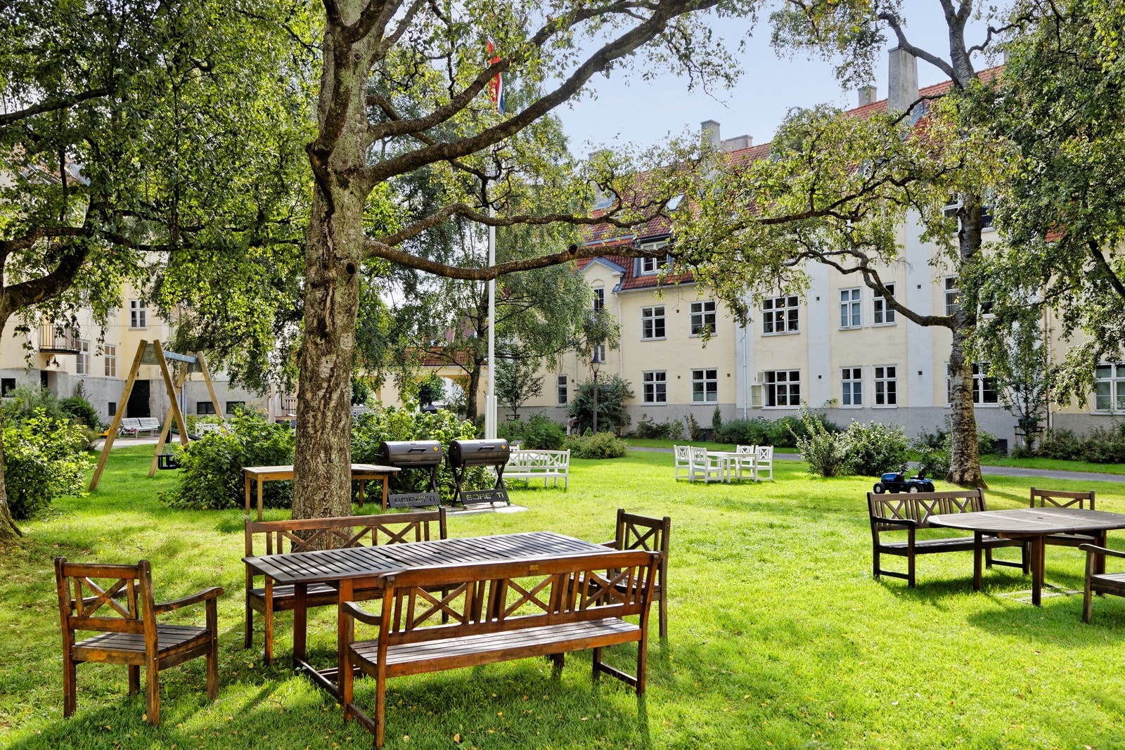 Idyllisk og rolig bakgård med flere sittegrupper, grill, lekeplass, sykkelparkering og frodige forhager med møblering og beplantning Galleribilde