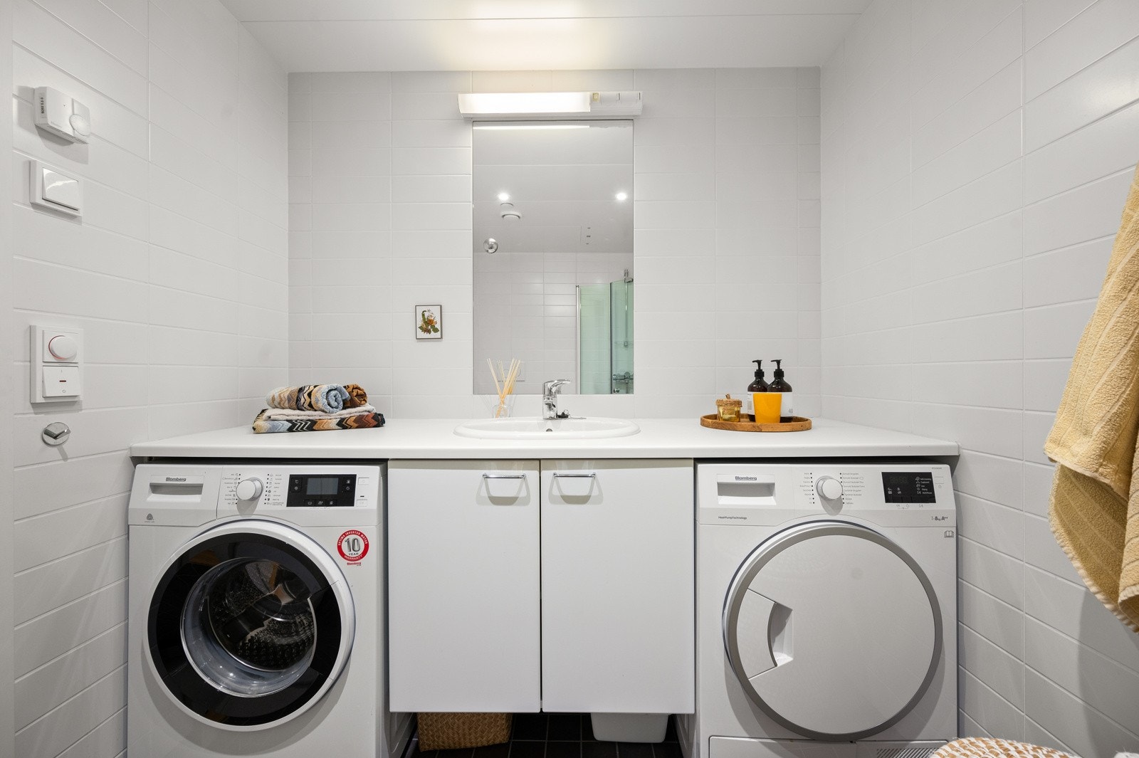 Baderomsinnredning med heldekkende benkeplate, skap, servant og opplegg for både vaskemaskin tørketrommel. Galleribilde