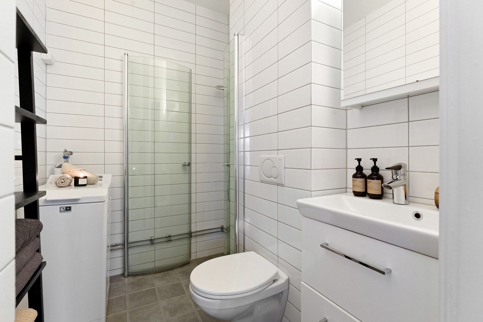 Baderommet er tidløst og funksjonelt, med flislagte vegger og gulv med varmekabler Galleribilde