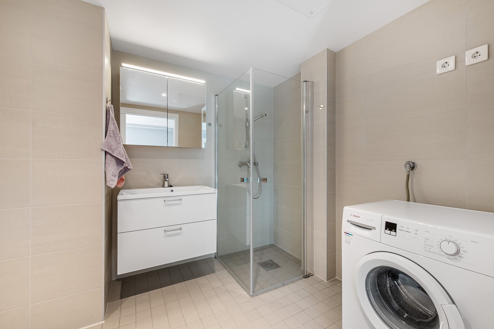 Badet har veggmontert servantskap, heldekkende servant med ettgreps armatur og speilskap. Opplegg for vaskemaskin. Galleribilde