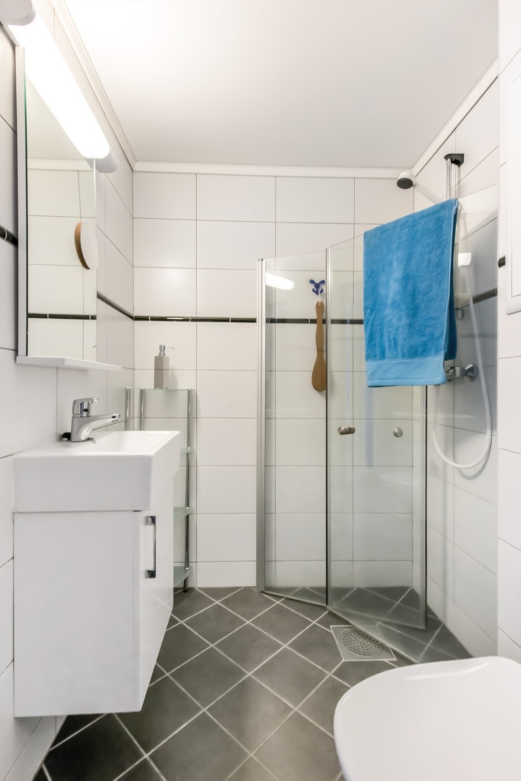 Badet er helfliset med varmekabler i gulv. Lyse, tidløse fliser og arealeffektiv innredning. Galleribilde