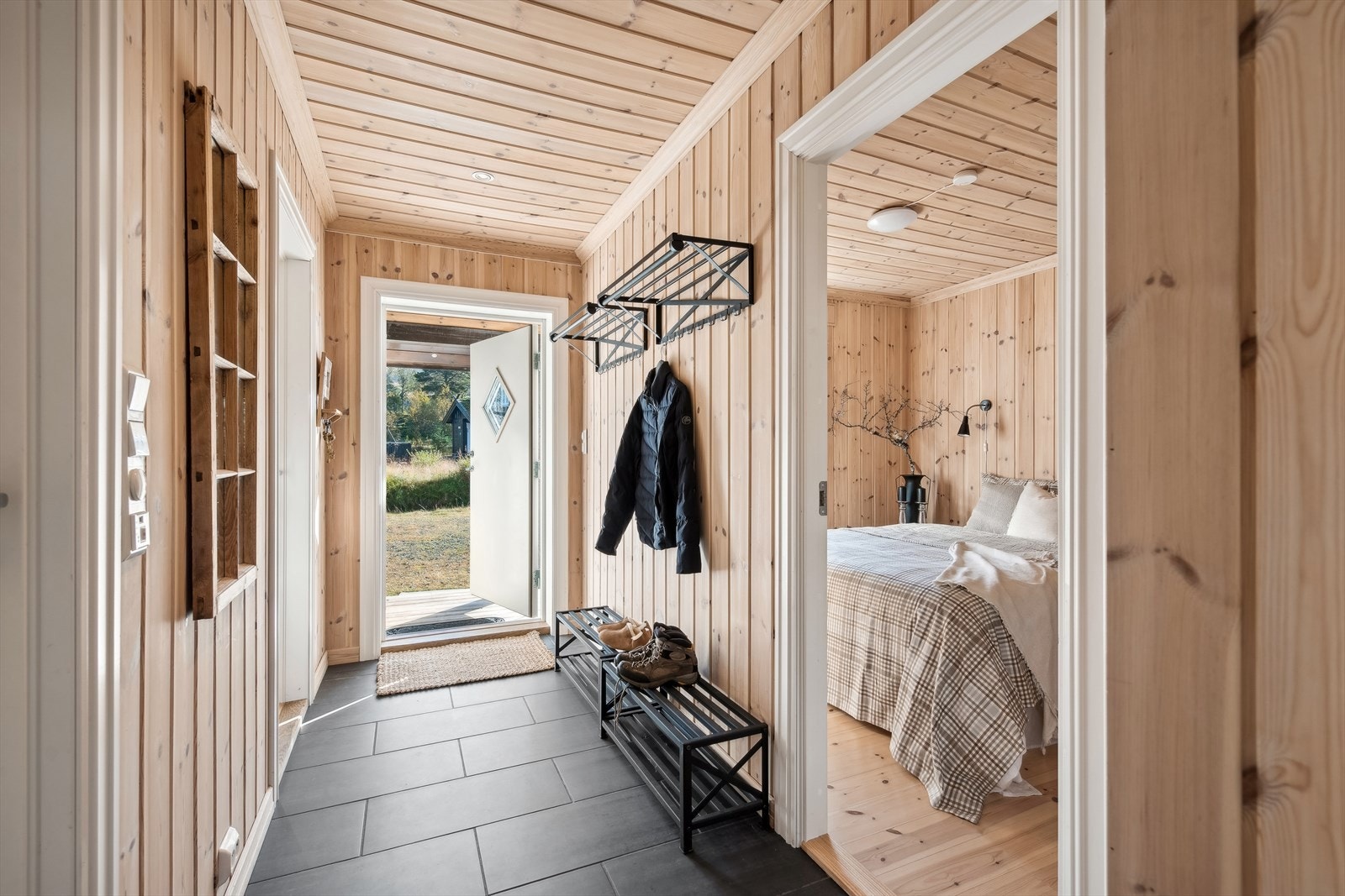 Romslig gang med flislagt gulv og rikelig plass til å henge fra seg klær. Det er også inngang til bod/vaskerom, som gir ekstra oppbevaringsplass for klær og sko Galleribilde