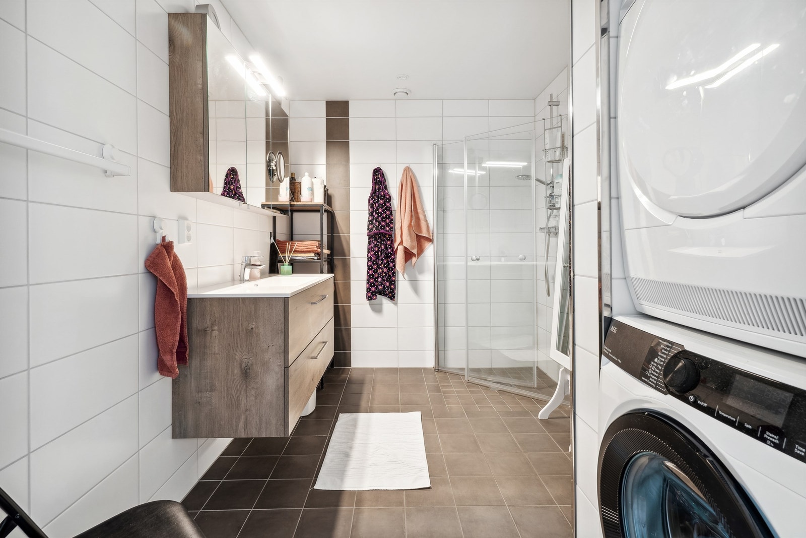 Flislagt bad med gulvvarme. Badet er utstyrt med baderomsinnredning, speilskap med lys og dusjhjørne med innfellbare dusjdører. Badet har opplegg for vaskemaskin. Innvendige bilder er fra tilsvarende leilighet i 4. etasje. Det er annen type flis her. Galleribilde