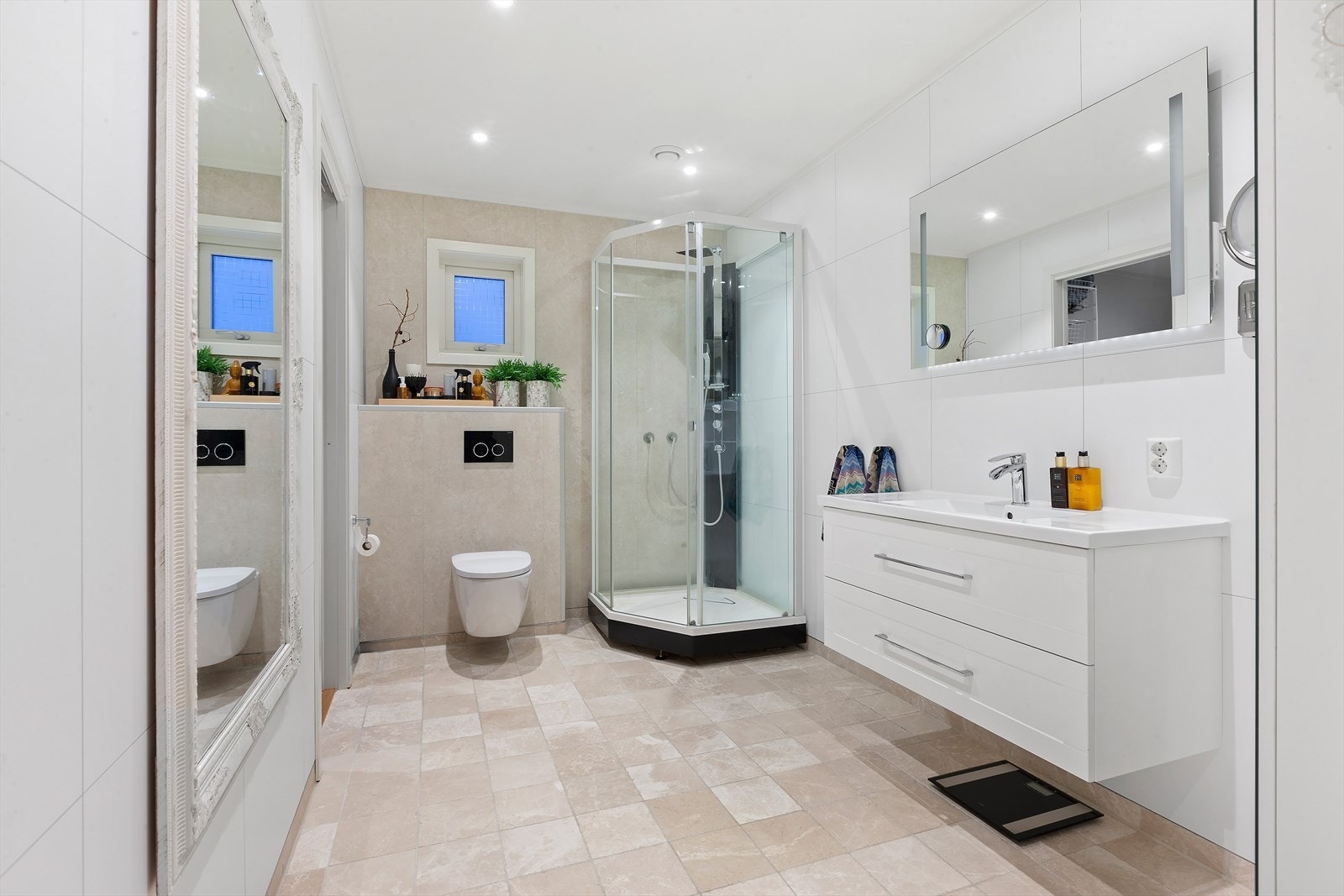 Lyst bad utstyrt med dusjkabinett, vegghengt wc og moderne baderomsinnredning. Varme i gulv. Galleribilde