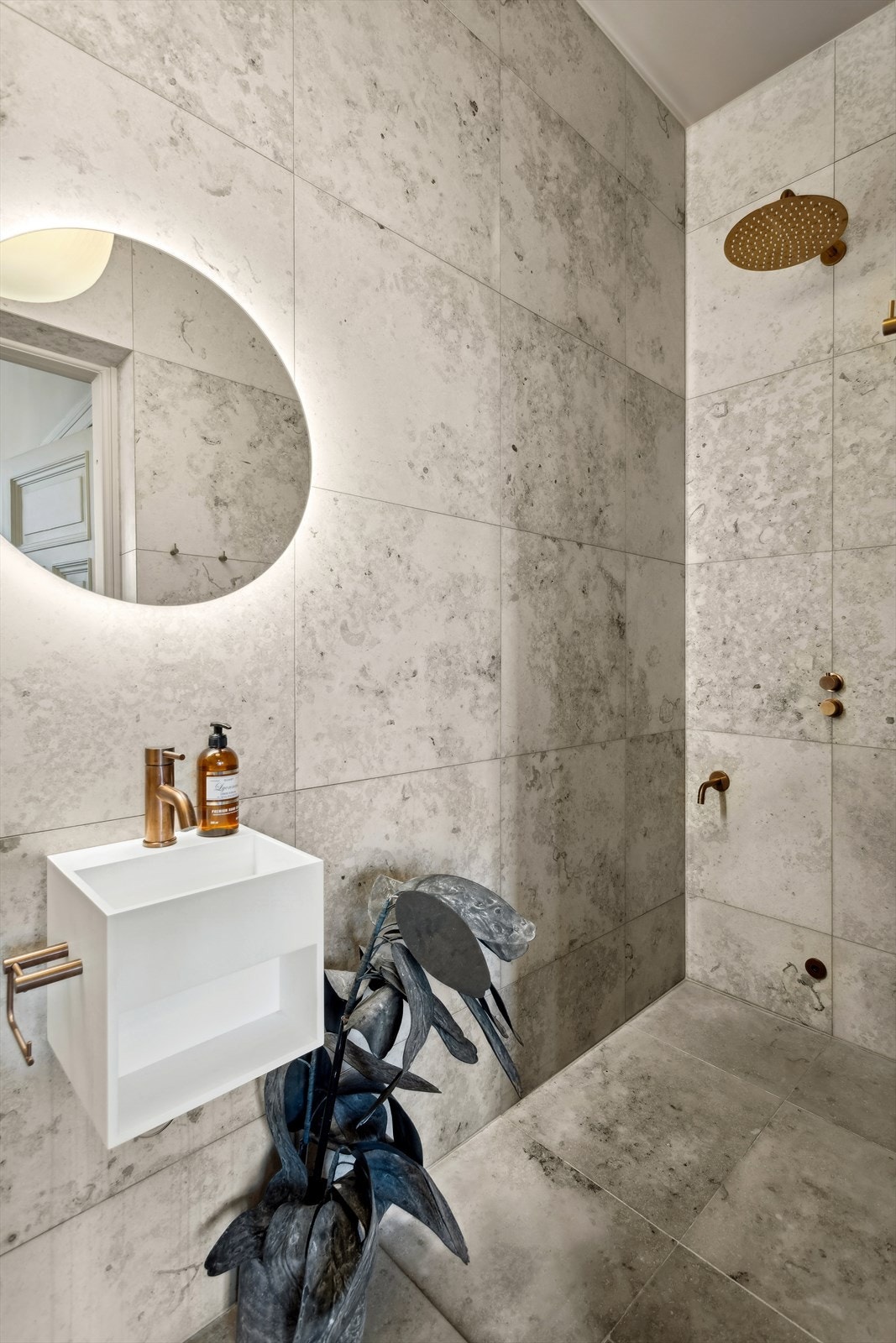 Badet er utstyrt med dusj på gulv, servant i helstøpt plate og veggfestet klosett med innebygget sisterne. Galleribilde