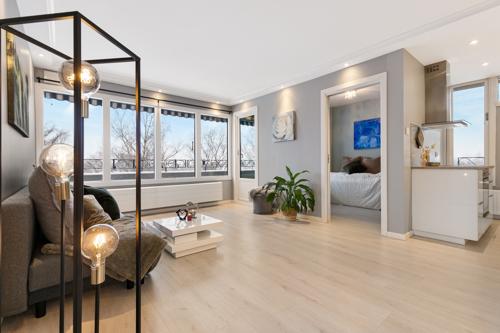 Stuen er stor og luftig med grå vegger, laminatgulv og store vinduer som slipper inn rikelig med naturlig lys. Spotter i taket gir en moderne og behagelig belysning. Galleribilde
