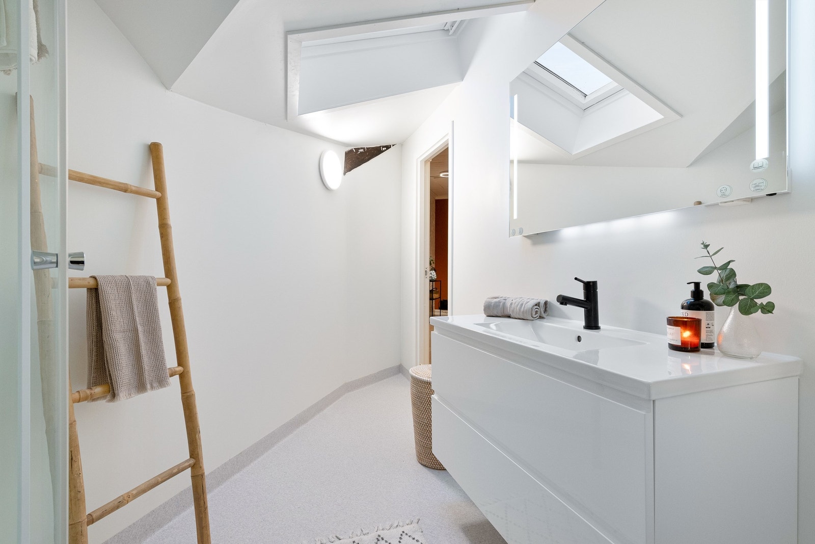 Lyst og delikat bad/wc med hvit baderomsinnredning med nedfelt vask og overskap med speil og lys. Galleribilde