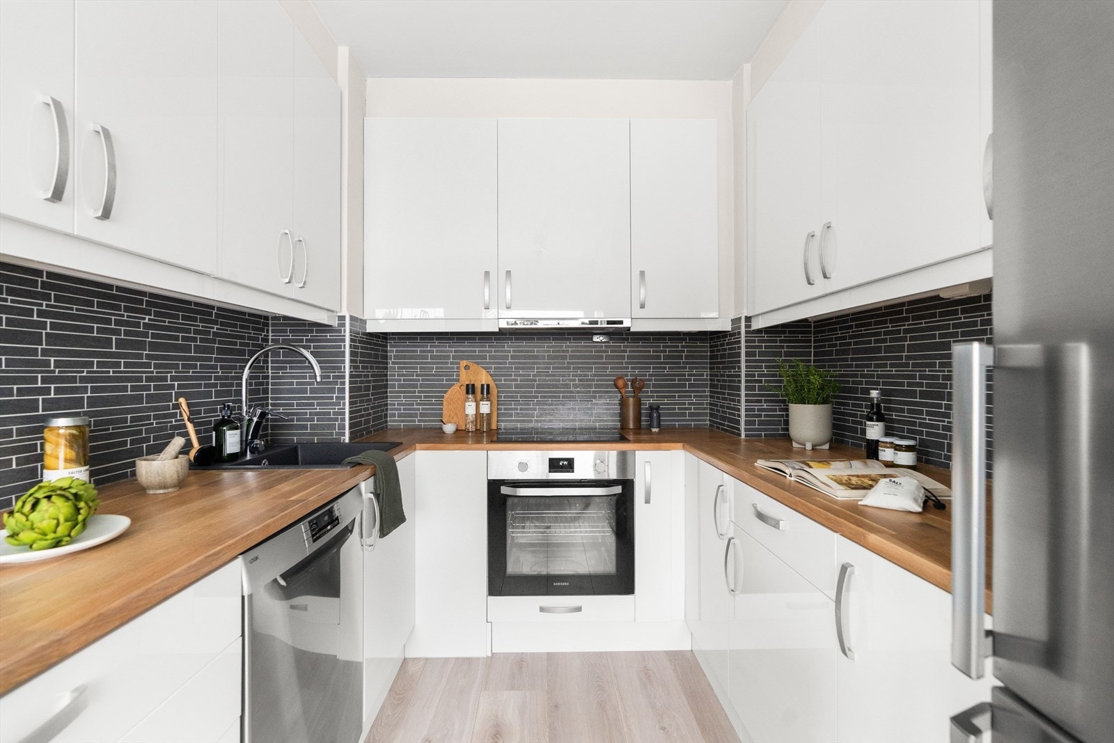 Kjøkkenet har hvite laminerte fronter, heltre benkeplate med oppvaskkum og svingbart blandebatteri fra Mora. Galleribilde