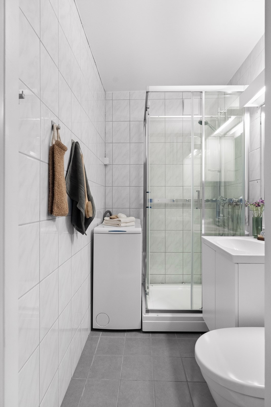 Videre er rommet utstyrt med dusjkabinett, gulvmontert toalett, opplegg for vaskemaskin, servantskap med hvite laminert fronter, hvit servant med blandebatteri fra Oras. Rommet har naturlig ventilasjon. Galleribilde