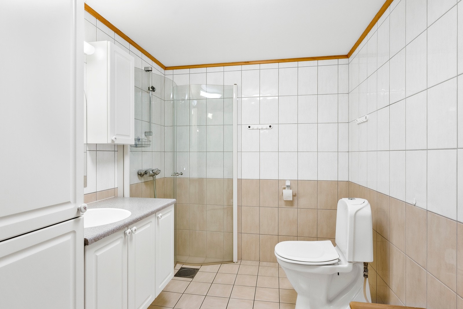 Badet har en lys, vegghengt servantinnredning med nedfelt servant og speil med overlys Galleribilde