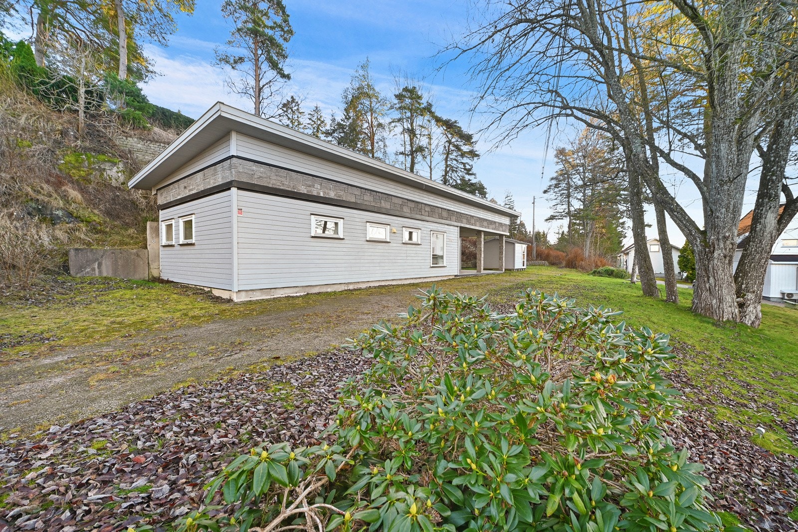 Huset har egen innkjørsel, og det er etablert trapper i terrenget mellom de to boligene. Galleribilde