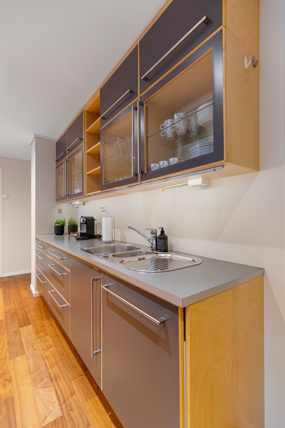 Det er montert takhøye overskap/vitrineskap med benkebelysning, og benkeplate i laminat med nedfelt stålservant. Fullintegrert oppvaskmaskin Galleribilde