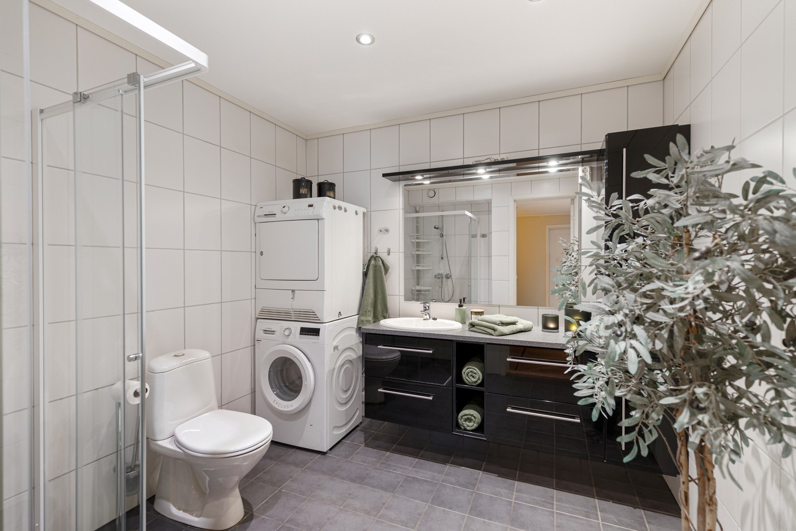 Badet er helfliset, og er utstyrt med downlights, gulvvarme, romslig baderomsinnredning, høyskap, toalett, dusjnisje og opplegg for vaskemaskin Galleribilde