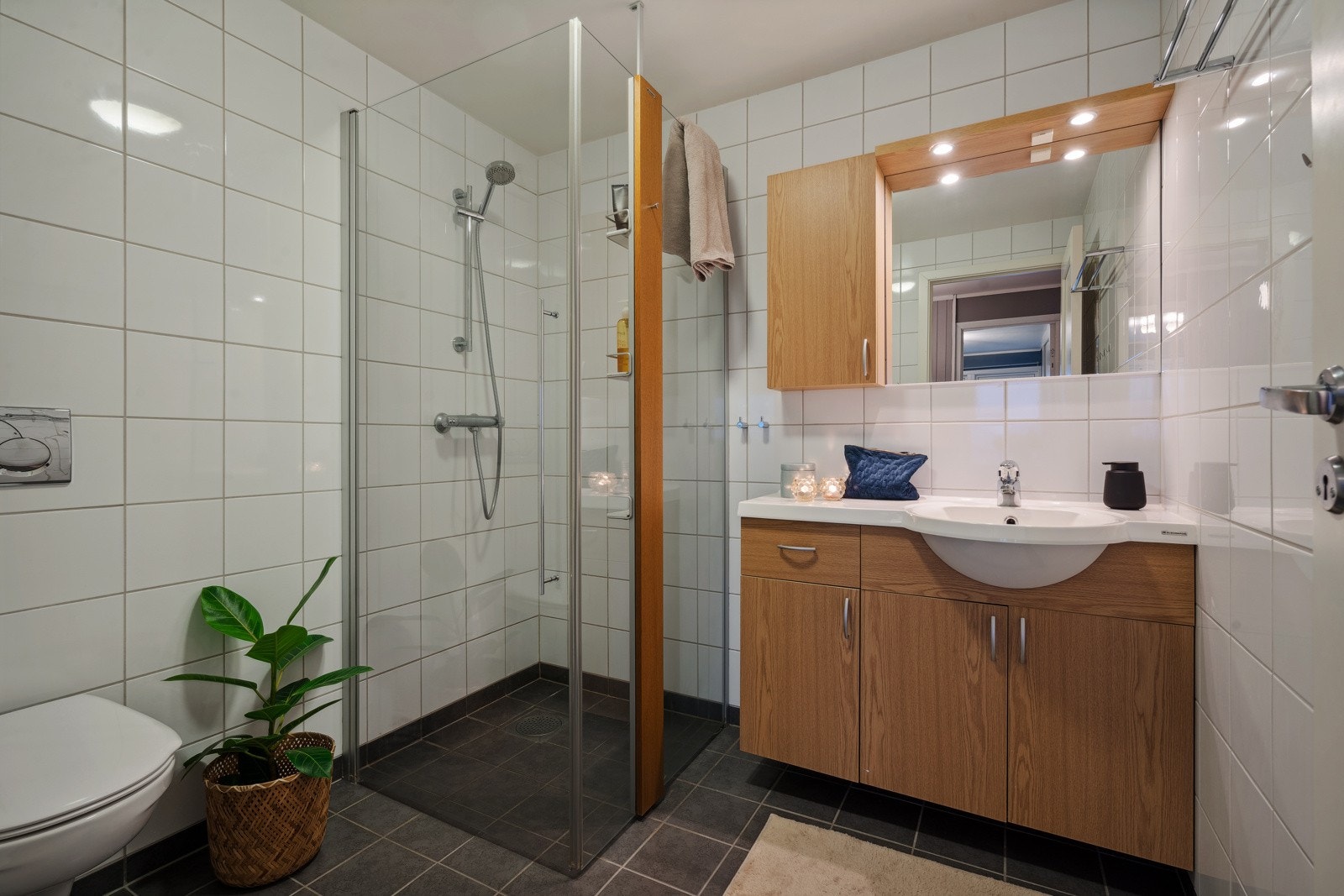 Badet er utstyrt med dusjhjørne, vegghengt toalett og et pent baderomsmøbel med over- og underskap. Galleribilde