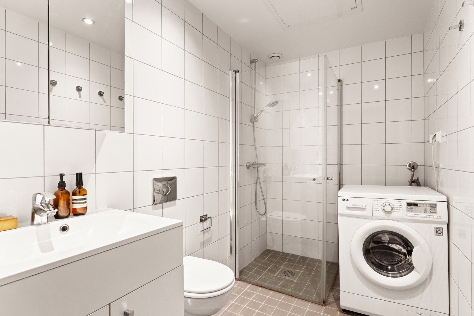 Delikat, flislagt bad som er innredet med dusjhjørne med inn- utadslående dusjvegger, servant m/underskap, overskap m/speilfronter og toalett. Galleribilde