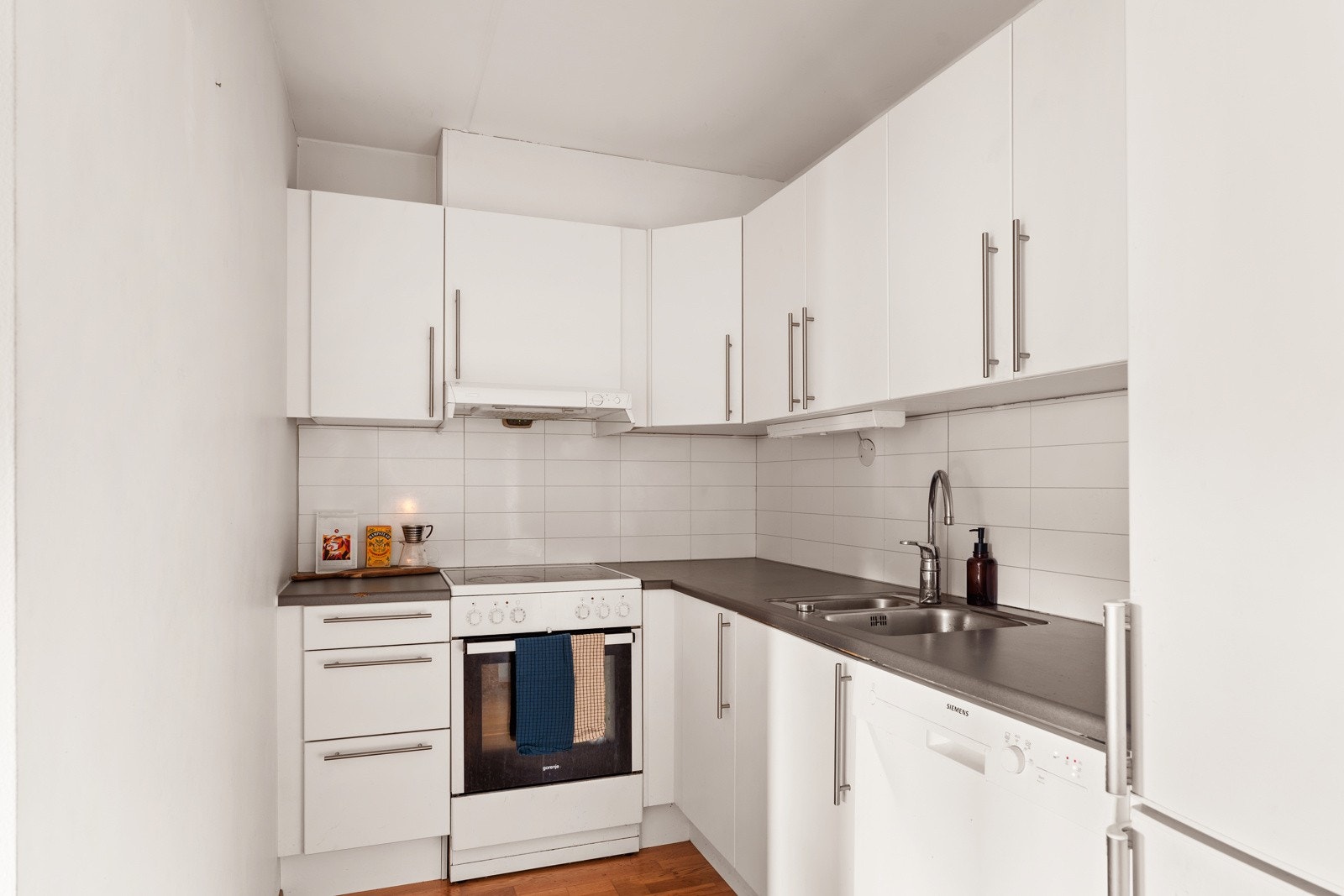 Praktisk og funksjonelt kjøkken i åpen løsning i stuen. Innredning fra Aubo med lyse slette lakkerte fronter, pen laminat benkeplate. Galleribilde