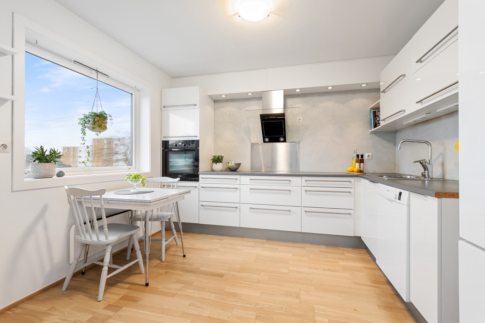 Tidløst kjøkken med stilrent design, store vinduer som gir naturlig lys, og funksjonelle løsninger for en effektiv hverdag Galleribilde