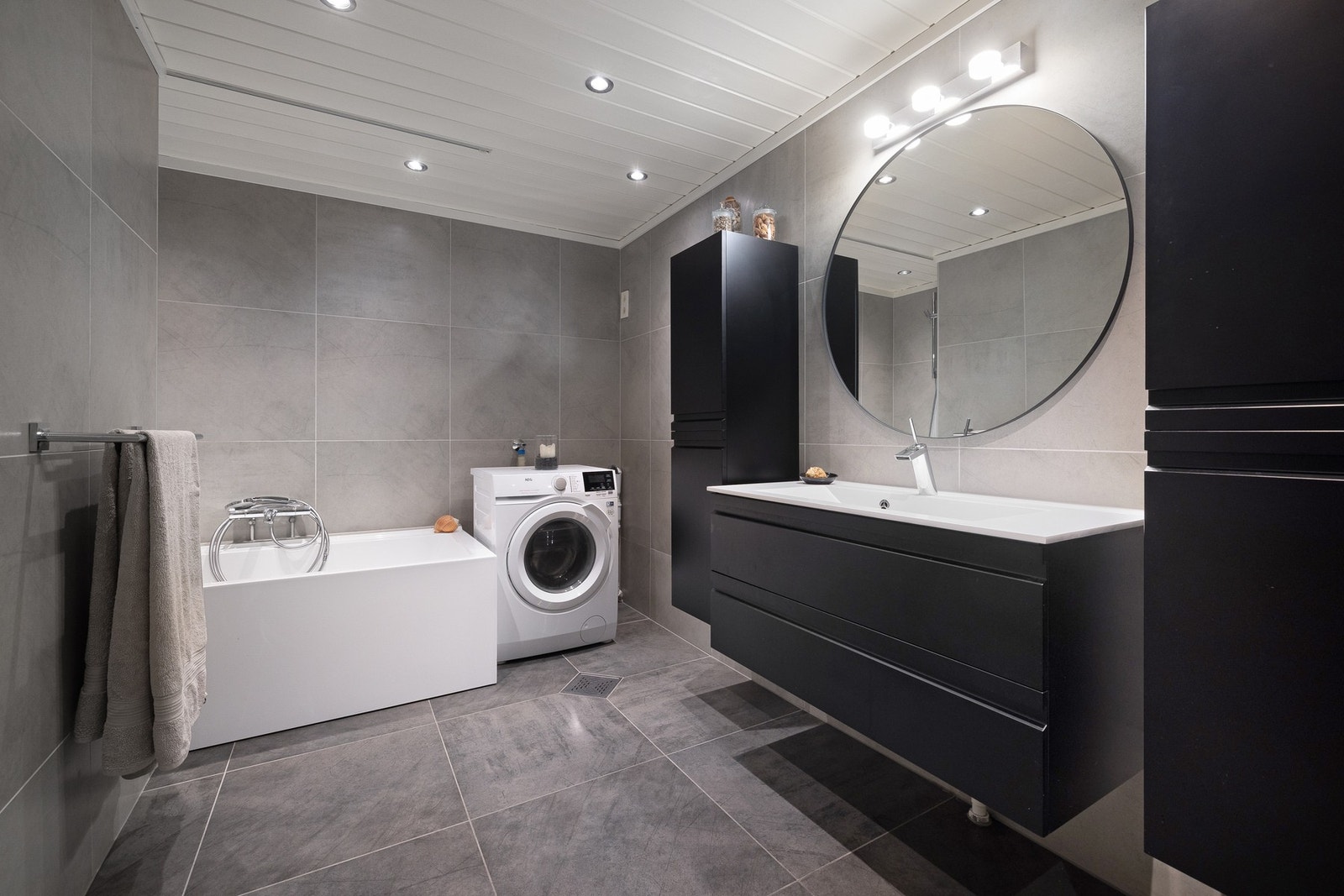 Moderne bad med flislagte overflater og himling med integrerte downlights som skaper en stilren og elegant atmosfære. Galleribilde