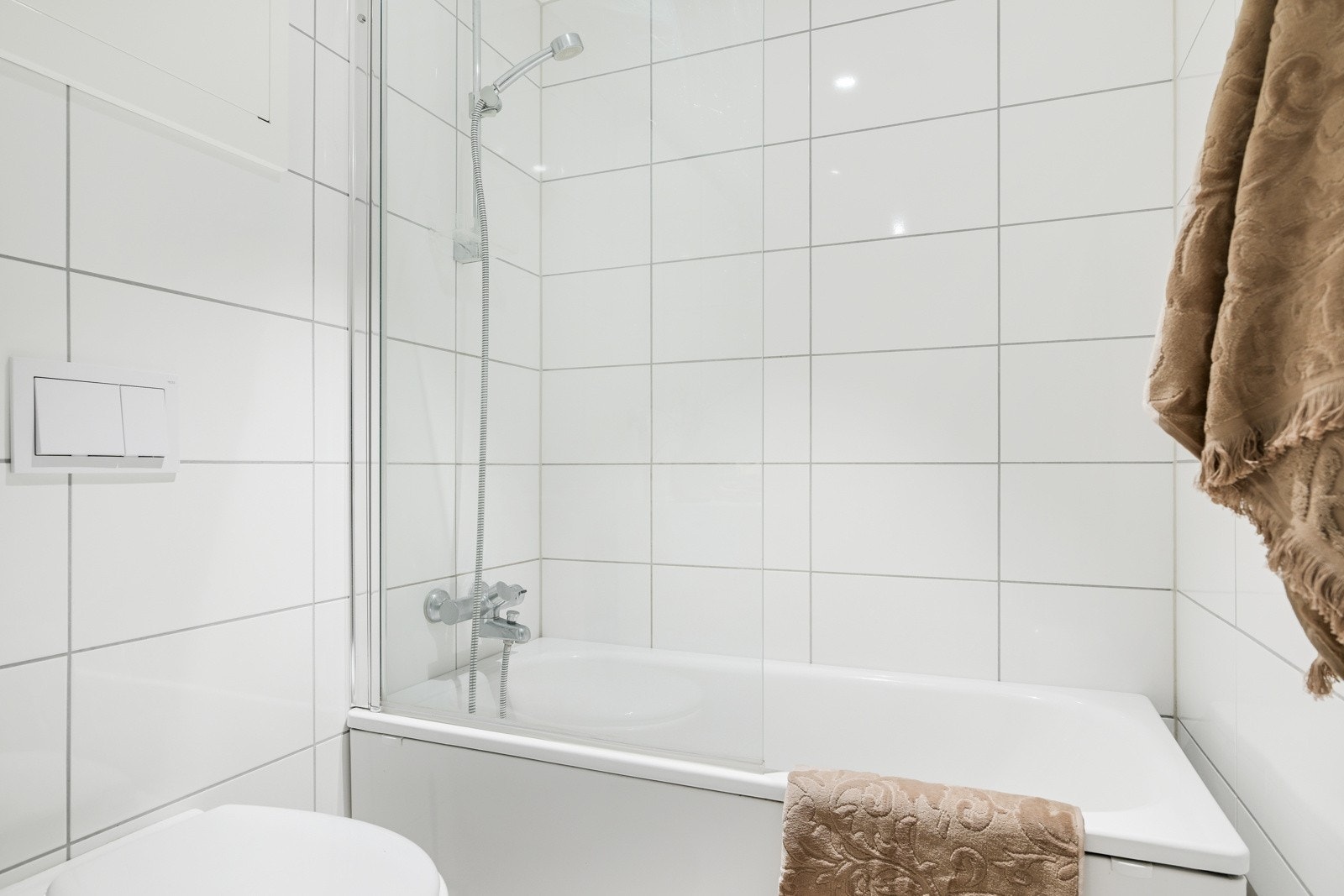 Badet har en fin baderomsinnredning med en heldekkende servant med underskap, vegghengt toalett og et flott badekar med glassdør. Galleribilde