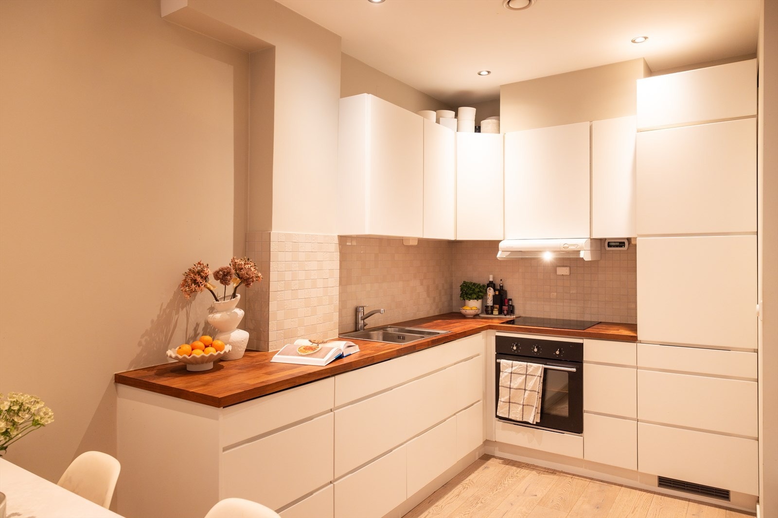 - Kjøkkeninnredning med glatte fronter. Heltre benkeplate med nedfelt vask- og skyllekum. Fliser over benkeplaten - Galleribilde