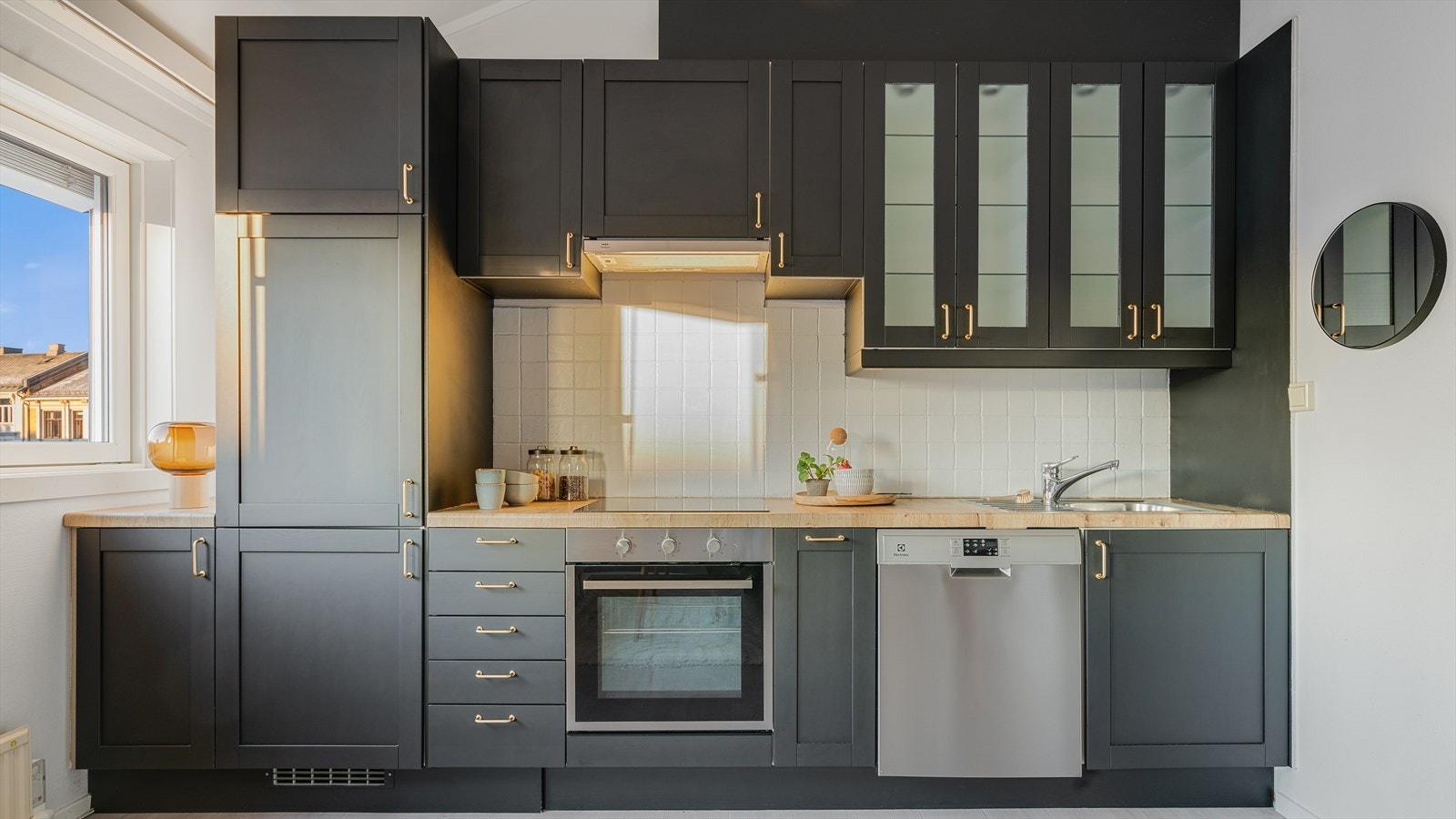 Pent kjøkken innredet med mørke, profilerte fronter og benkeplate av laminat Galleribilde