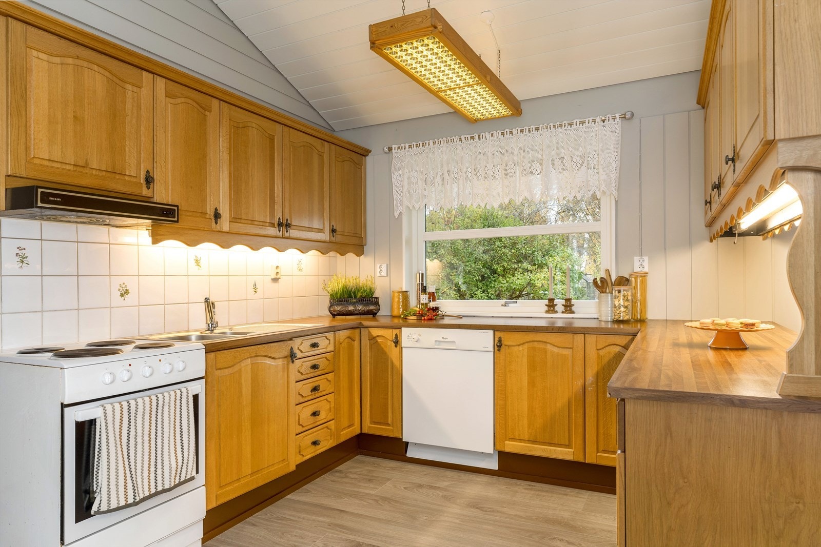 Kjøkkeninnredning med profilerte, lakkerte fronter og laminat benkeplate. Kjøkkenet har god benkeplass, over- og underskap. Galleribilde