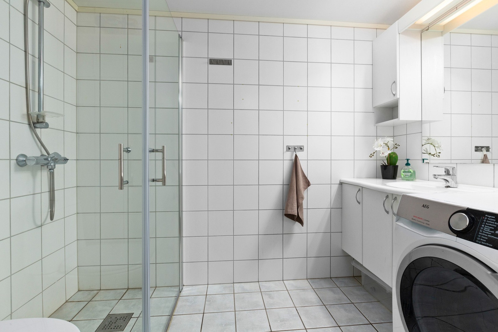 Det flislagte badet fungerer også som vaskerom, med en praktisk og nøytral innredning. Galleribilde
