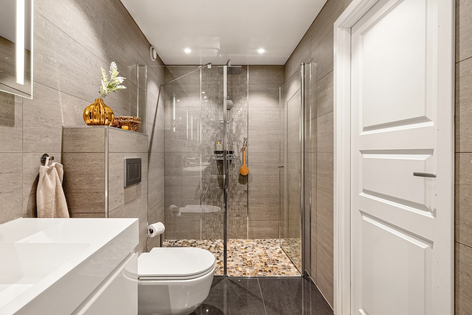 Flott design bad ekstra stor dusjsone med tropedusjarmatur og rullesteinsgulv. Veggmontert wc med softclose. Galleribilde