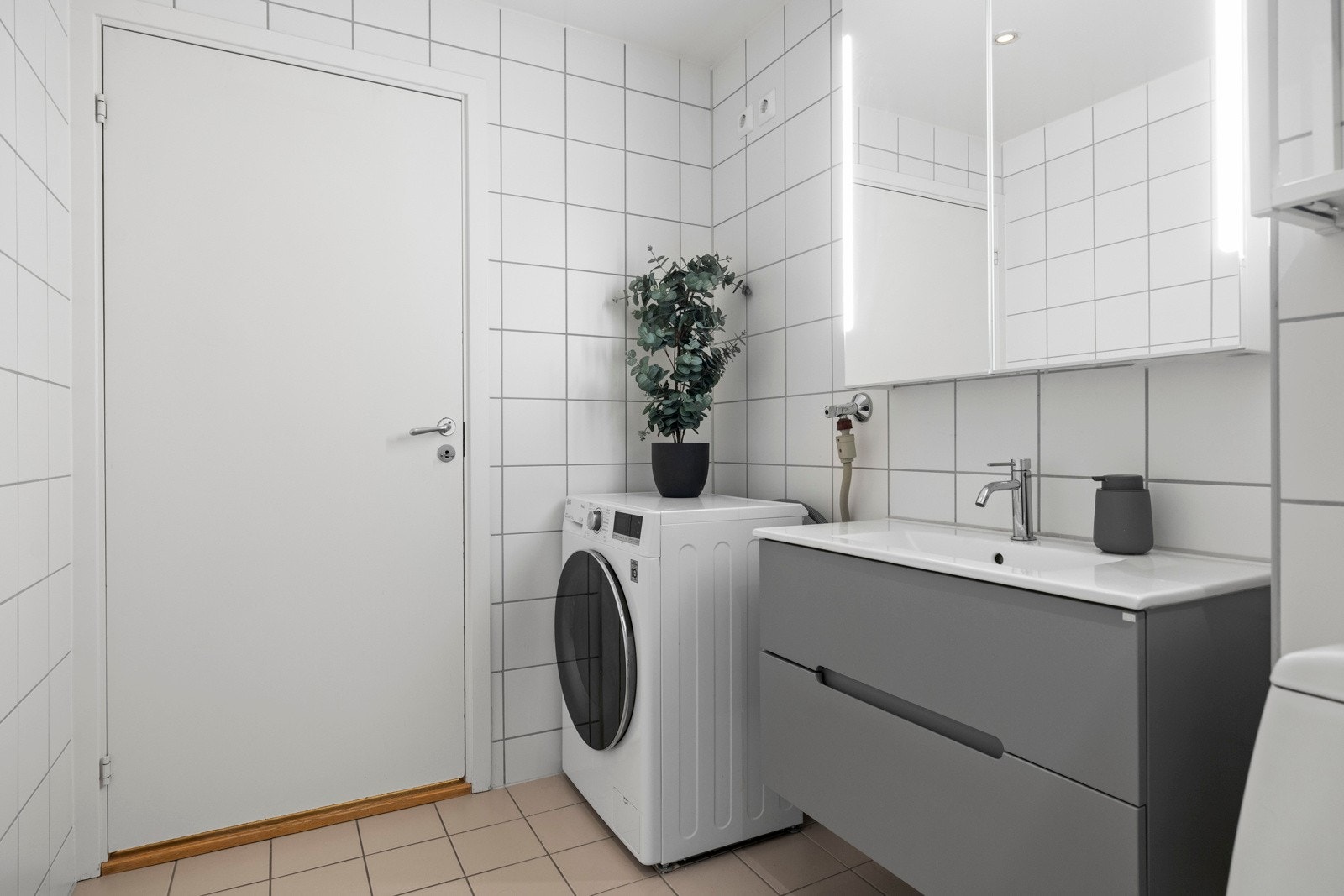 Rommet er utstyrt med en stilren baderomsinnredning med speil og integrert belysning. Hvor det i tillegg finnes det opplegg for vaskemaskin og et gulvmontert klosett. Galleribilde