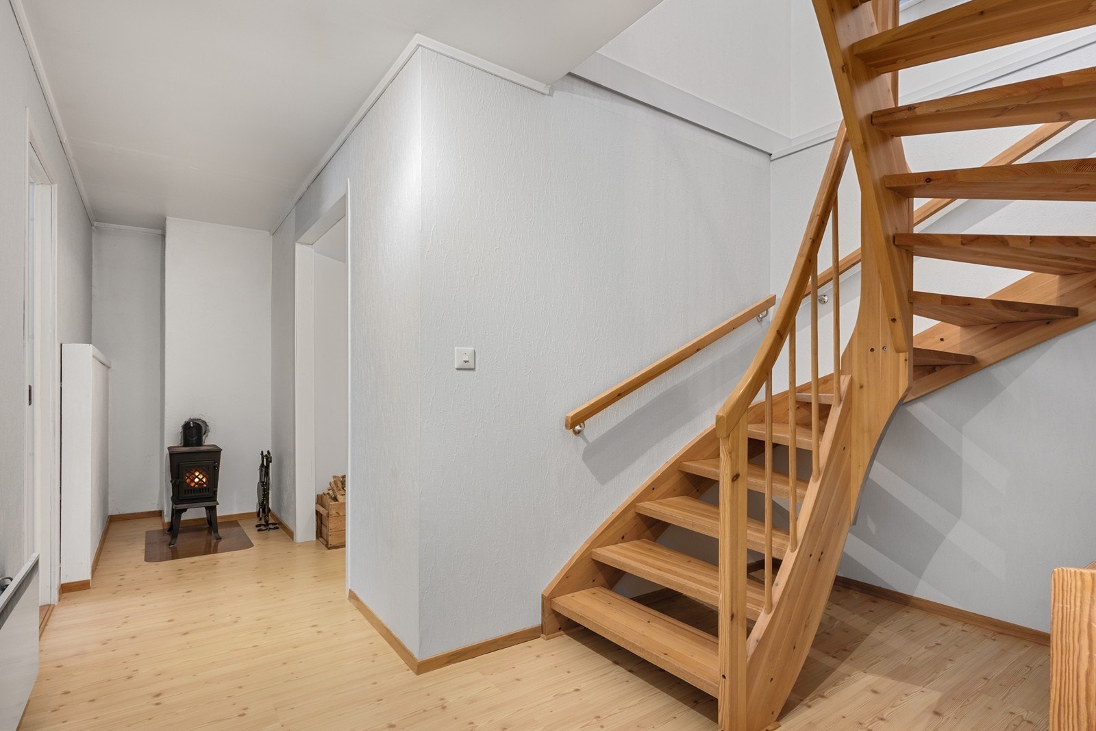Via åpen heltretrapp er det adkomst til boligens underetasje, der trappegangen har en eldre Jøtul peisovn. Galleribilde