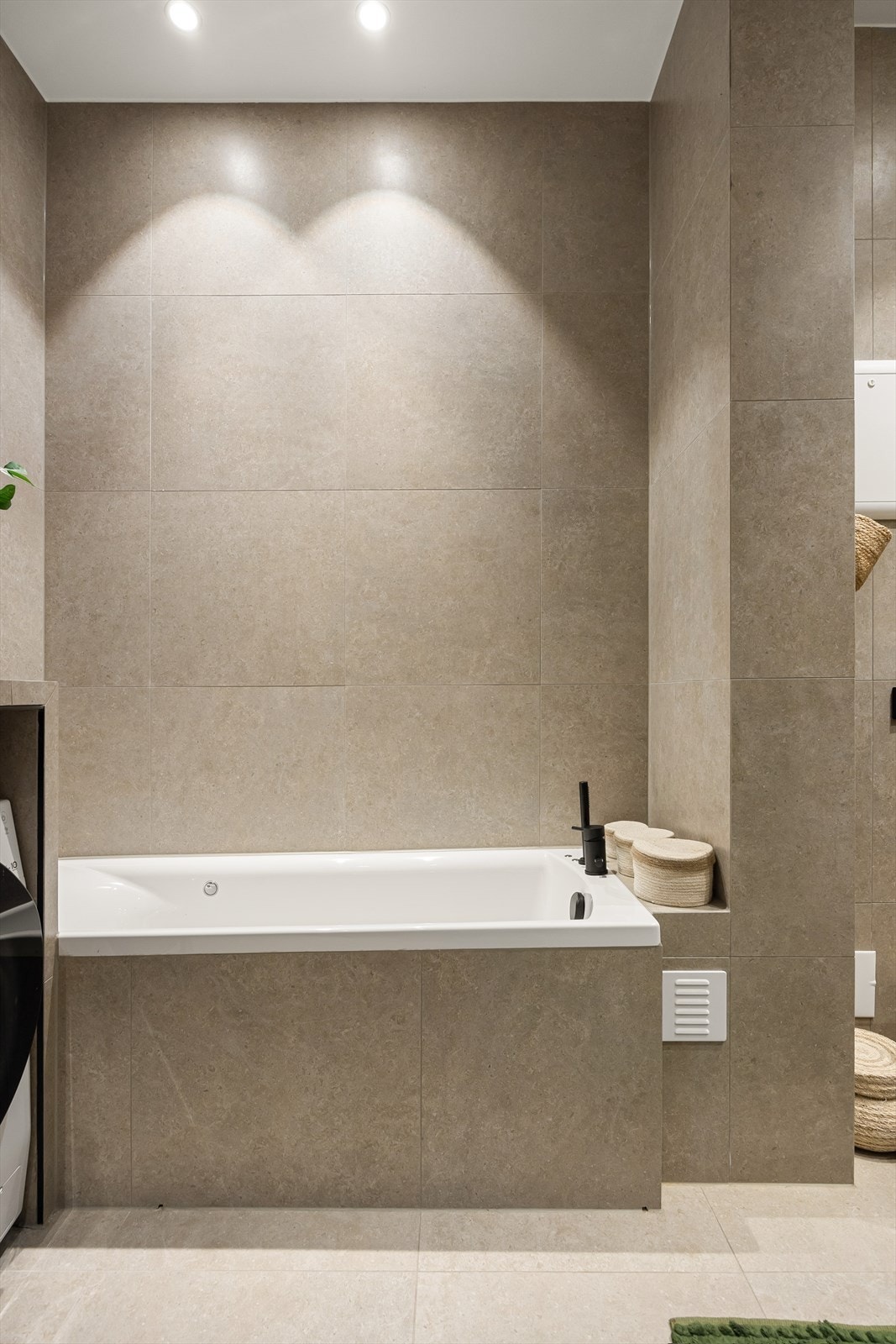 Badet er utstyrt med et innebygd og flislagt massasjebad, komplett med to inspeksjonsluker, synlig avrenningsspalte, dusjbatteri med tappekran og en praktisk hånddusj. Galleribilde