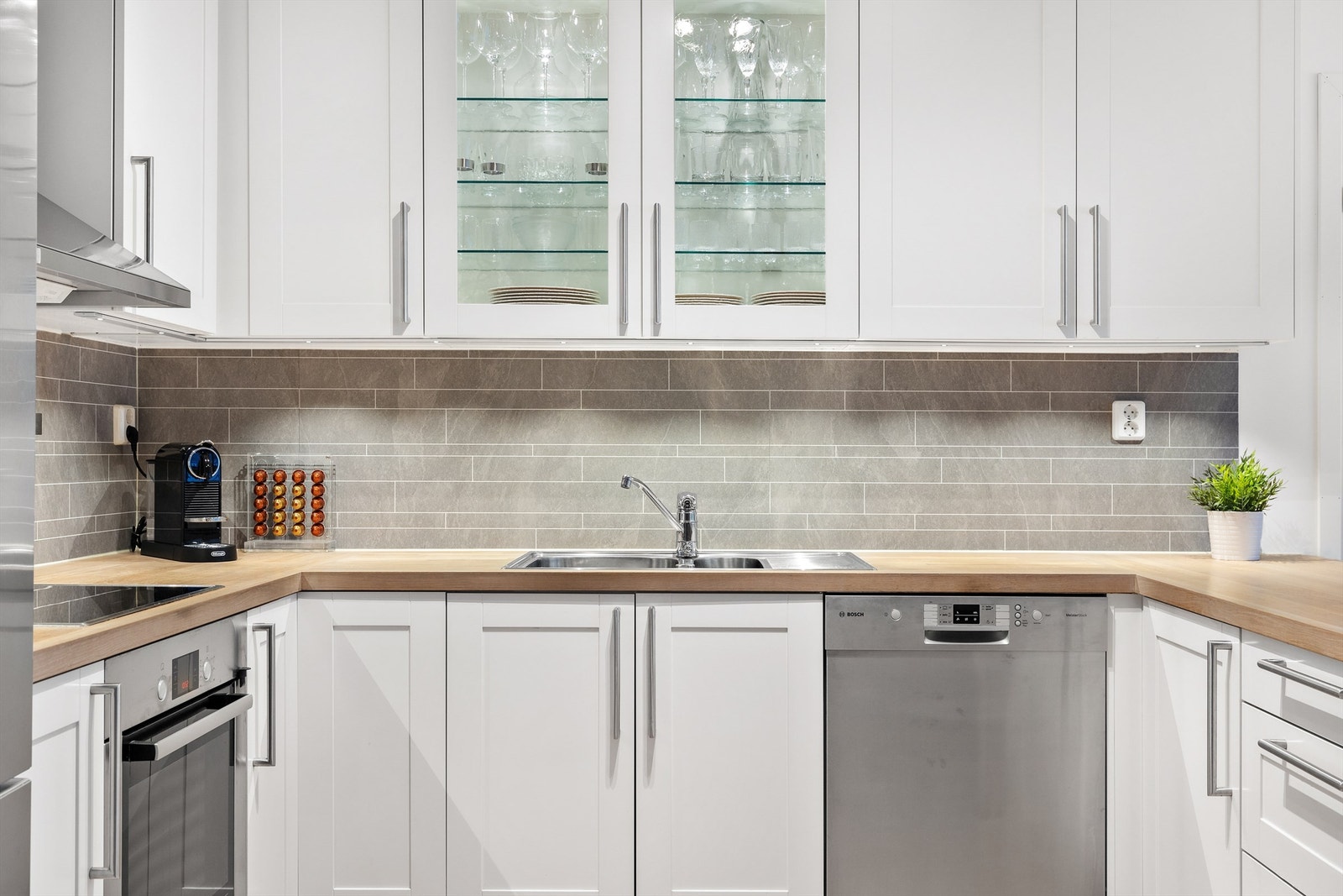 Integrert stekeovn og platetopp, oppvaskmaskin i benk og frittstående kjøleskap med fryser. Galleribilde