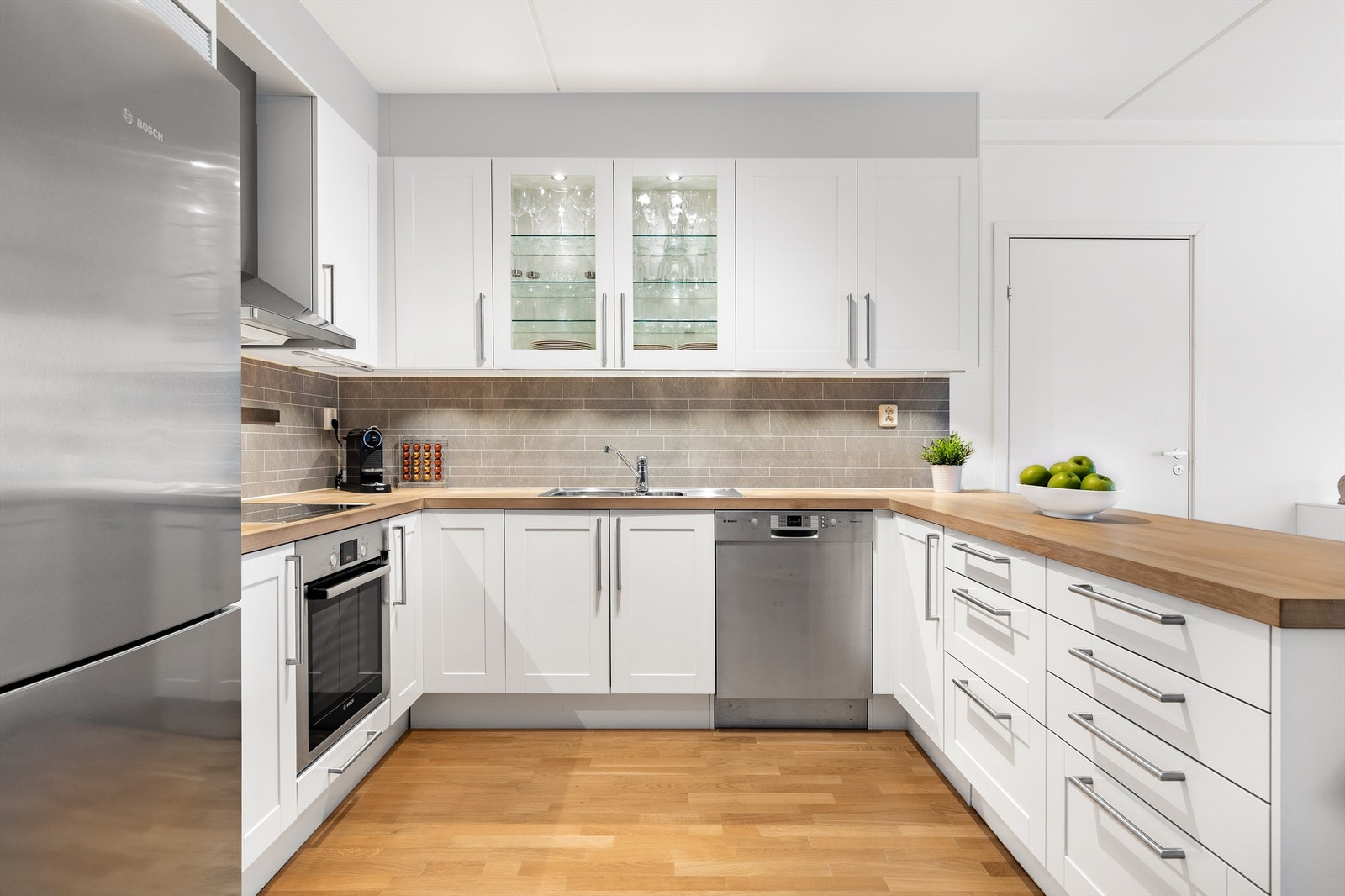 Åpen kjøkkenløsning. Innredningen er fra byggeår med profilerte fronter. Benkeplate av treverk. Galleribilde